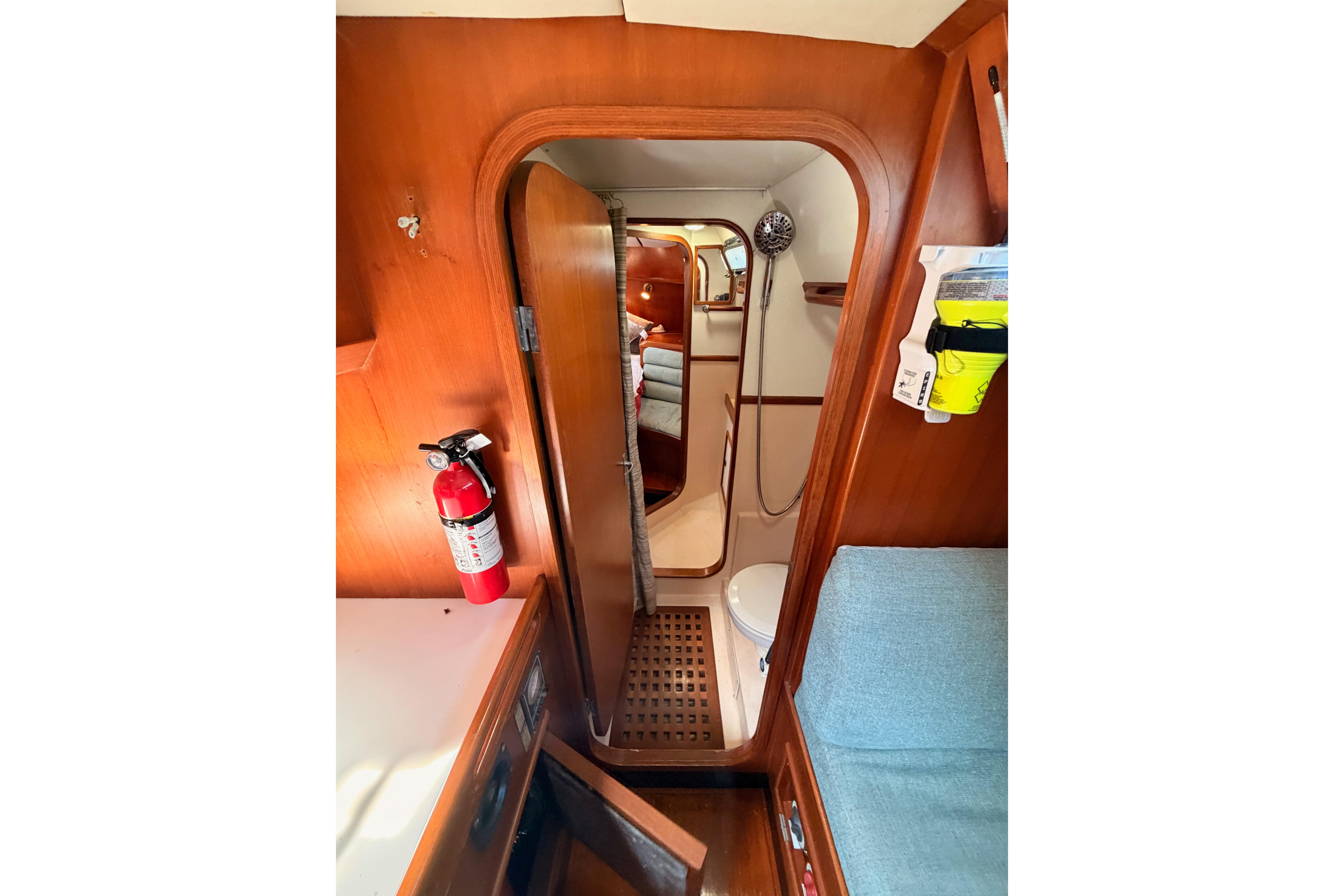Interior of 1991 Hylas 51 yacht, featuring wooden cabinetry, a fire extinguisher, and a compact bathroom.