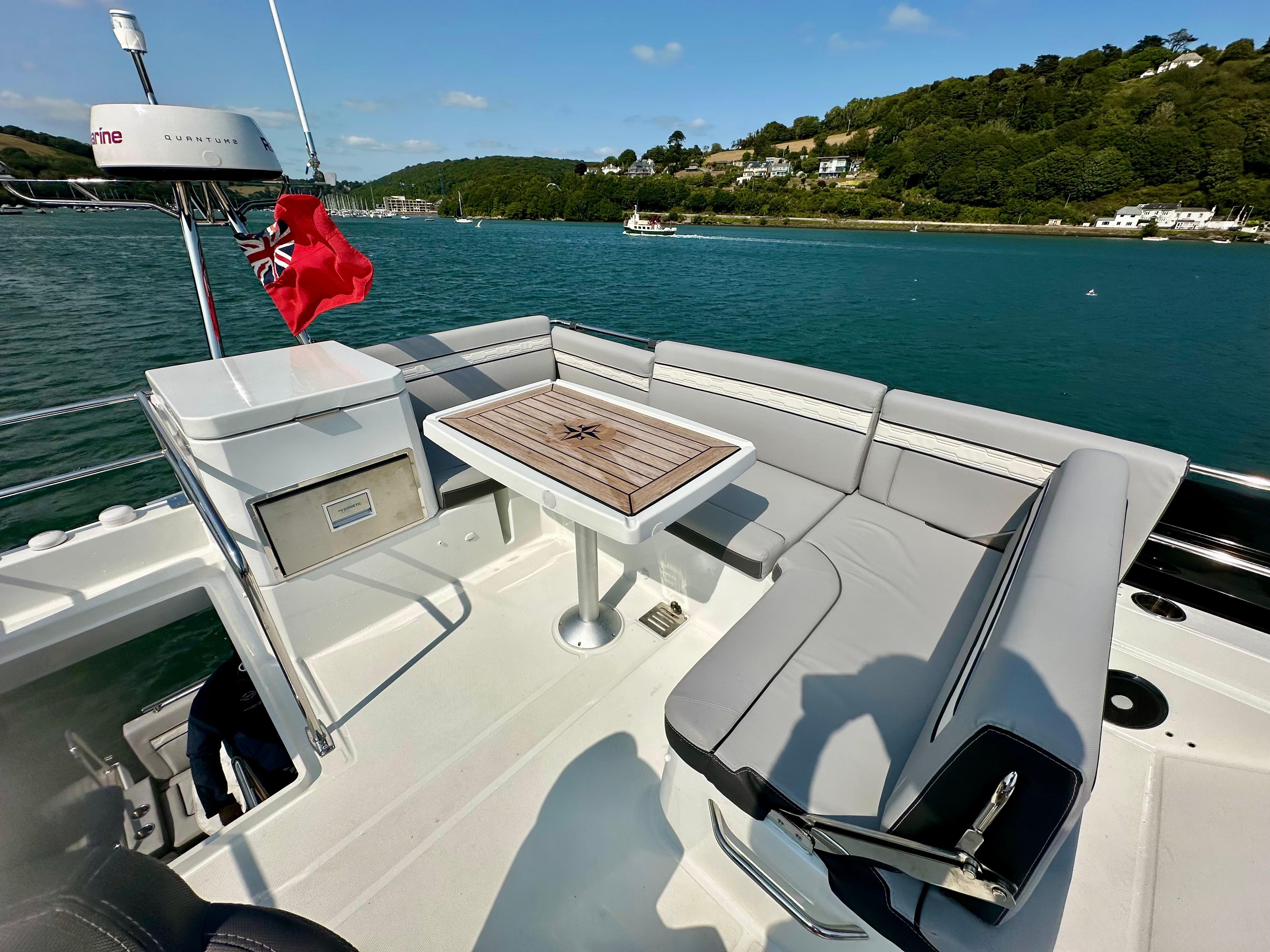 Flybridge seating area on 2024 Jeanneau Merry Fisher 1295, overlooking scenic water and hills.