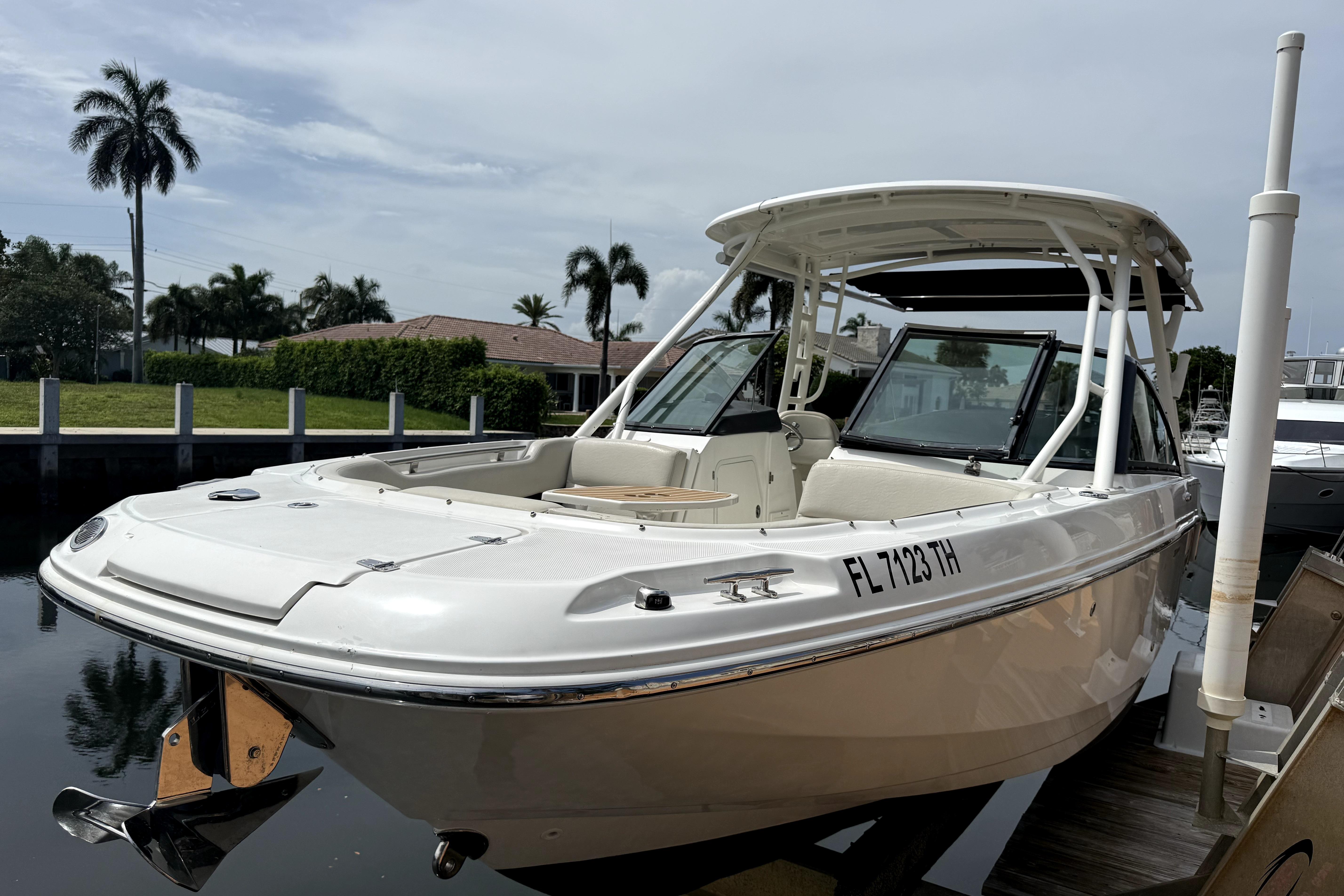 2018 Boston Whaler 230 Vantage boat docked near palm trees and waterfront homes.