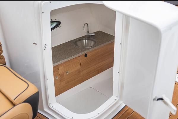 Manufacturer Provided Image: Interior of 2026 Hurricane SunDeck 2690 OB boat featuring a compact sink and wooden cabinetry.
