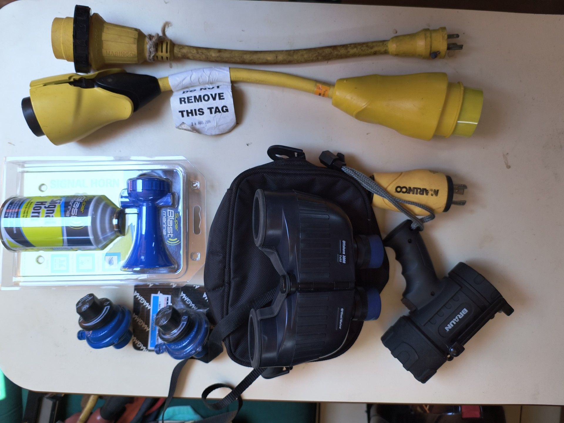 Boat accessories with cables, binoculars, and flashlight on table.