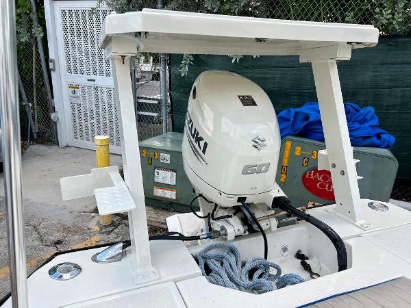 1986 Hoog Comet 14 boat with Suzuki 60 outboard motor in a storage area.