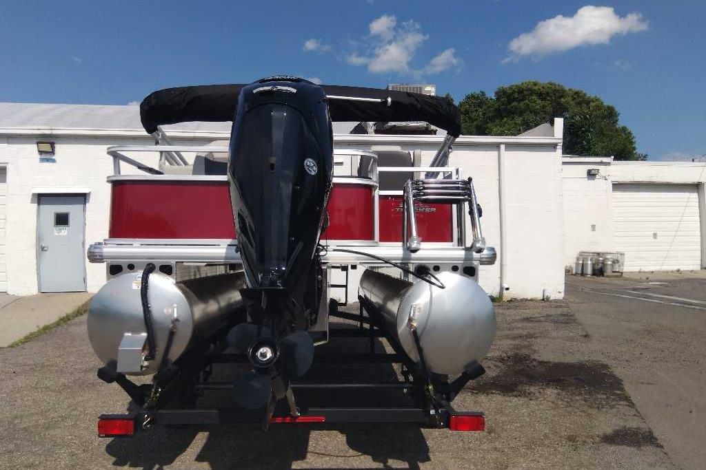 2026 Sun Tracker Bass Buggy 18 DLX pontoon boat, rear view with motor, parked outdoors.