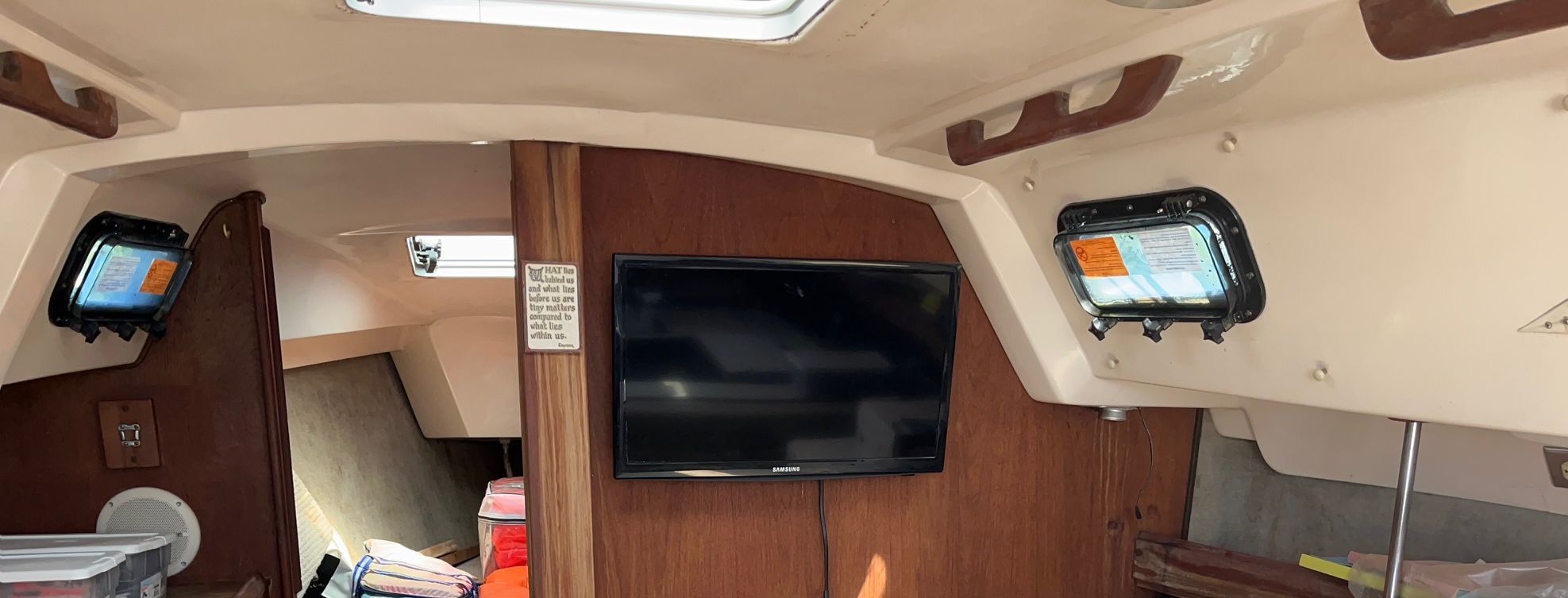 Interior of a 1985 Hunter 30 sailboat with wood paneling and a flat-screen TV.