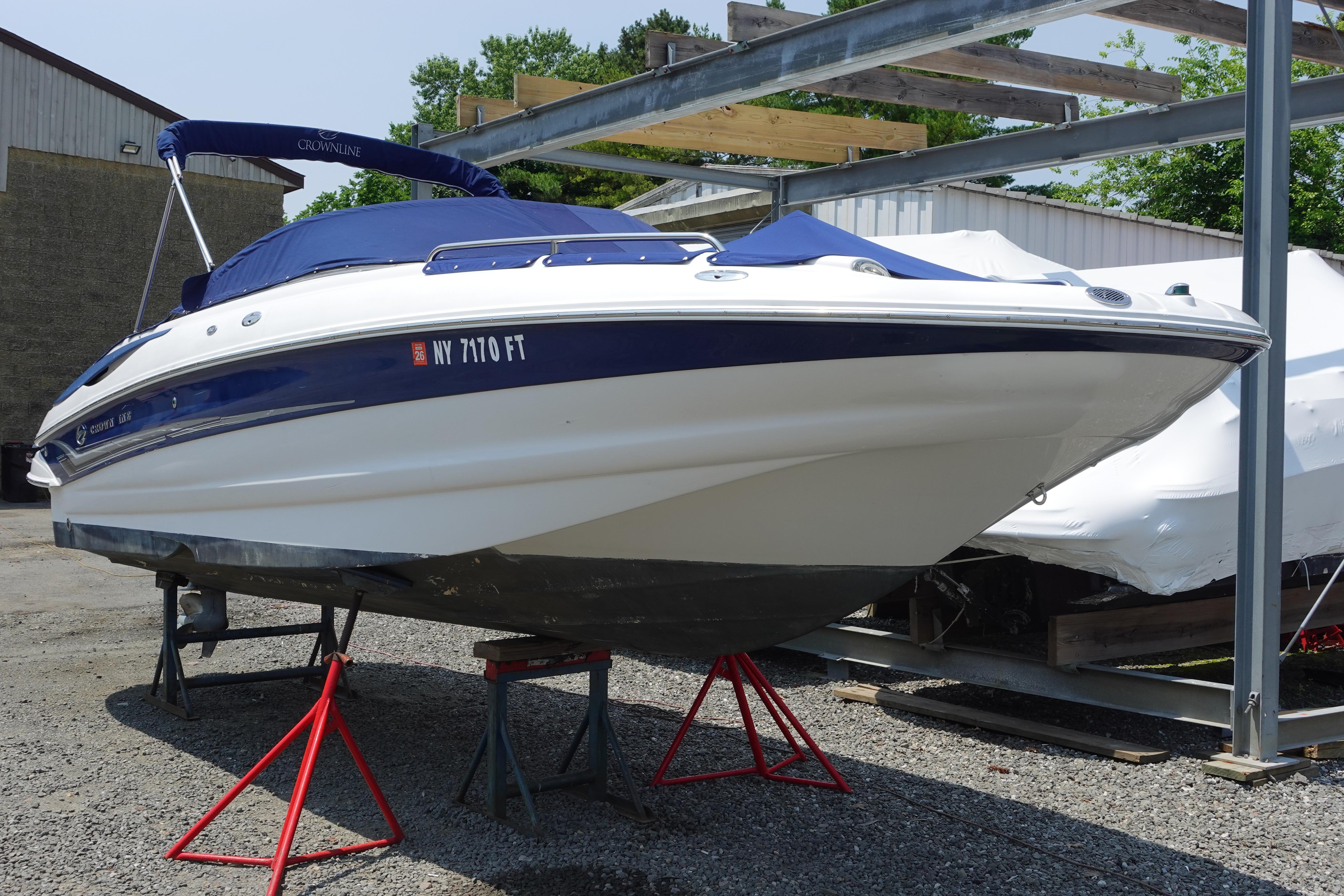 2004 Crownline 240 EX boat on stands, blue cover, outdoor storage.