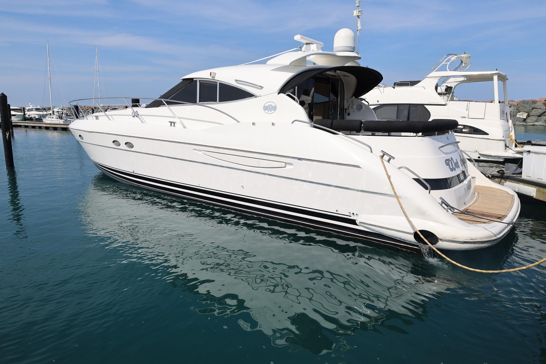 1999 Neptunus 54 Express yacht docked in a marina, side view.