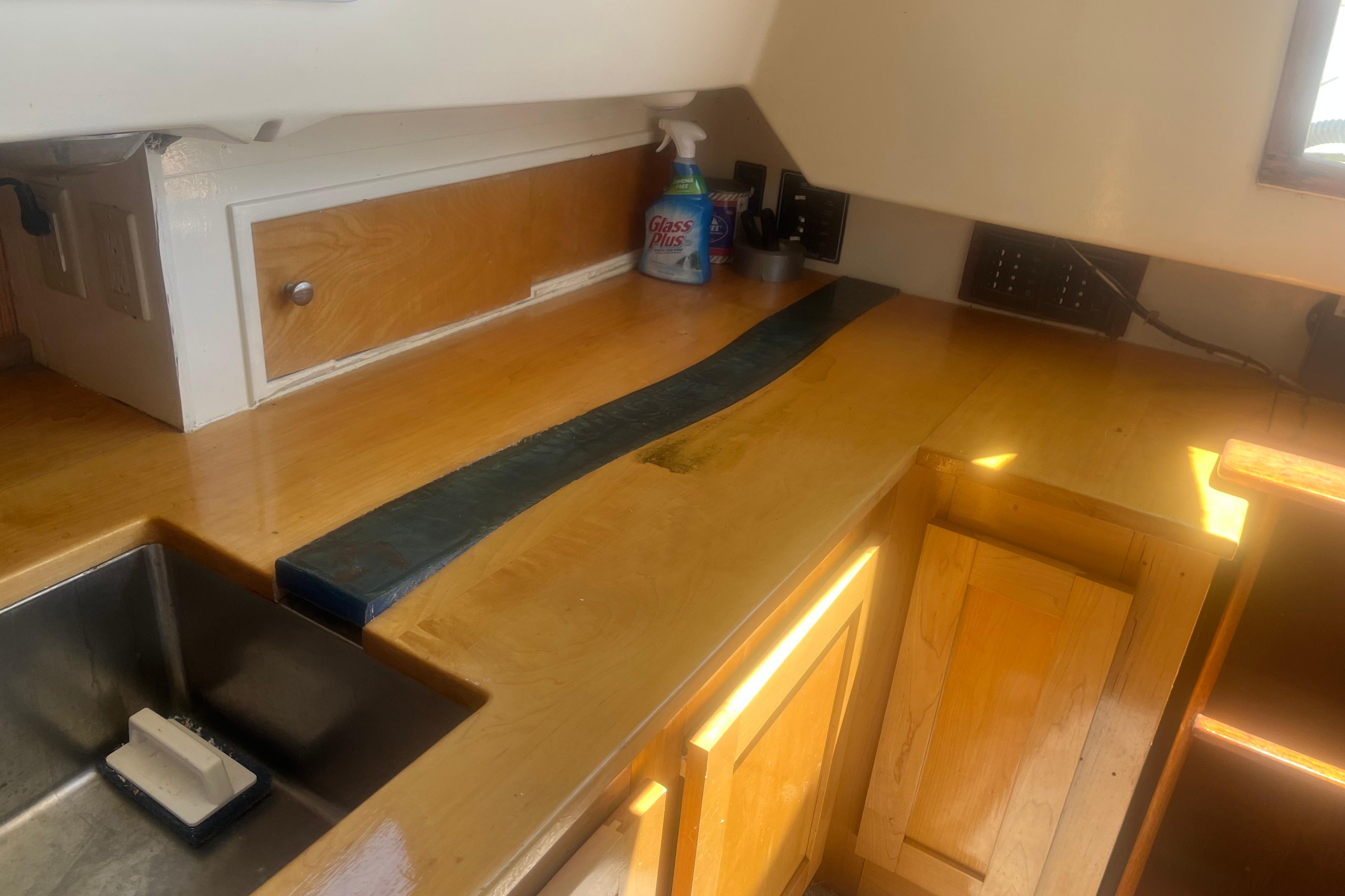 Interior of a 1972 C&C 30 sailboat galley with wooden cabinets and countertop.