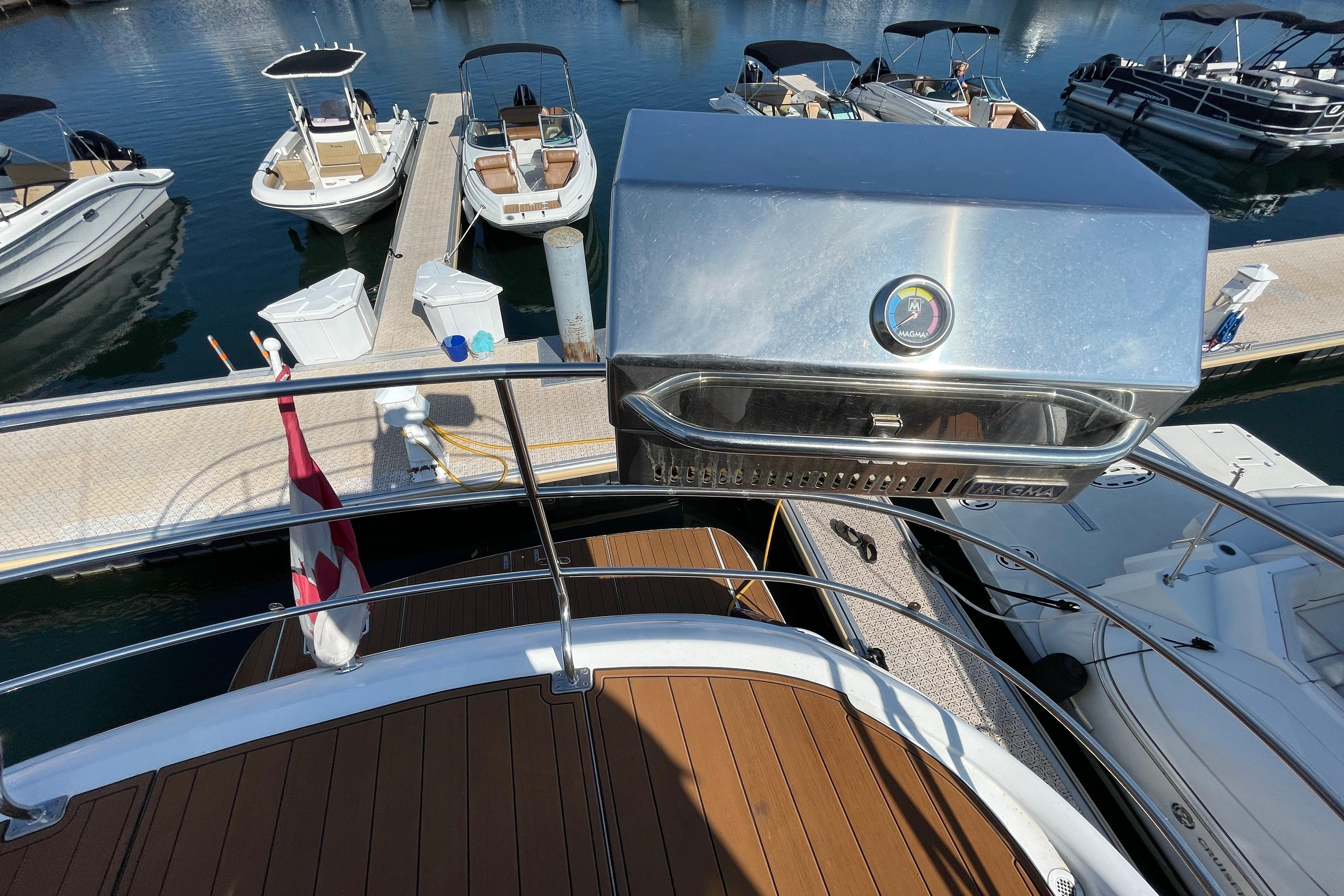 2002 Carver 570 Voyager Pilothouse yacht with a Magma grill, docked at a marina.