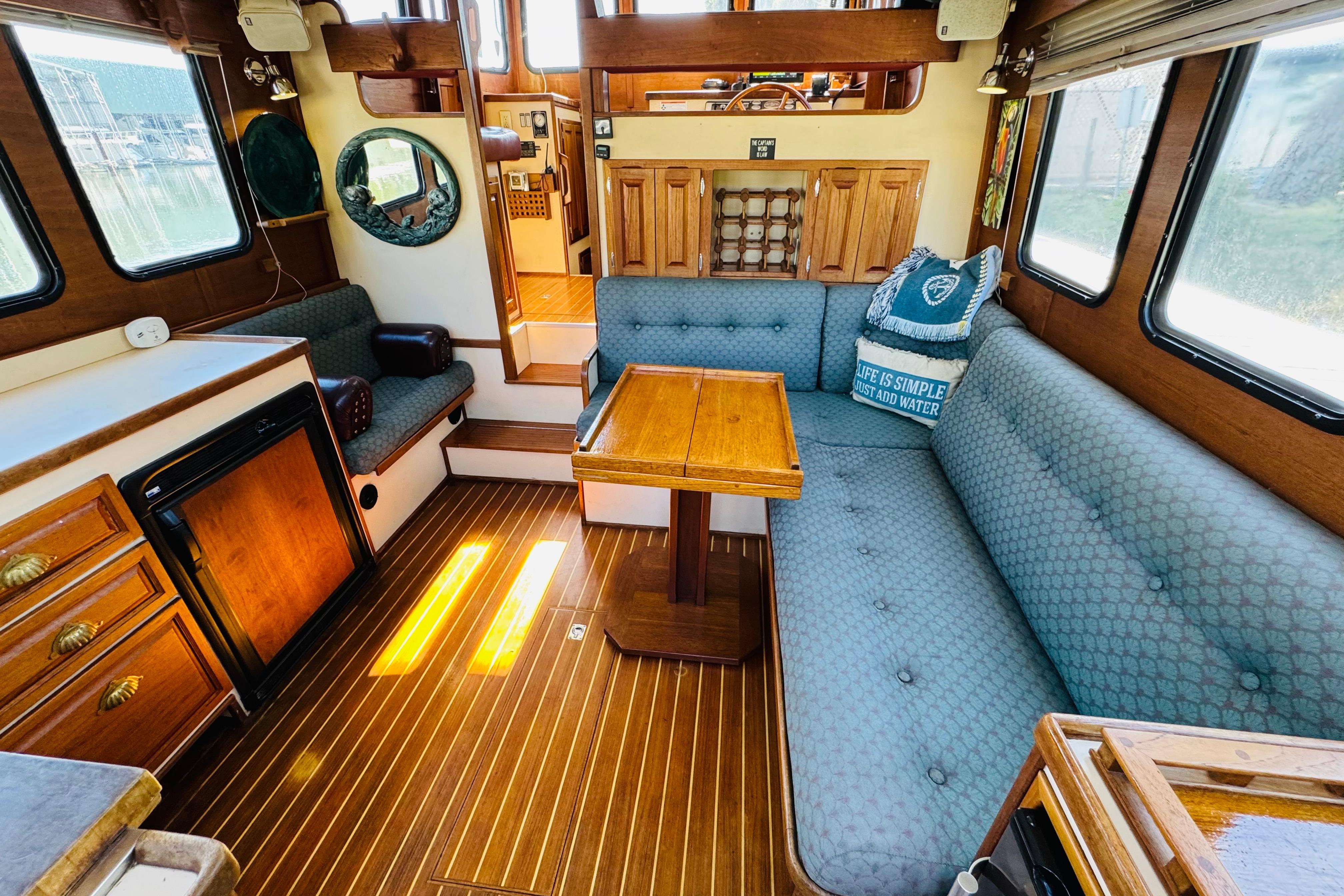 Cozy interior of a 1996 Nordic Tug 32 with wood accents and blue seating.