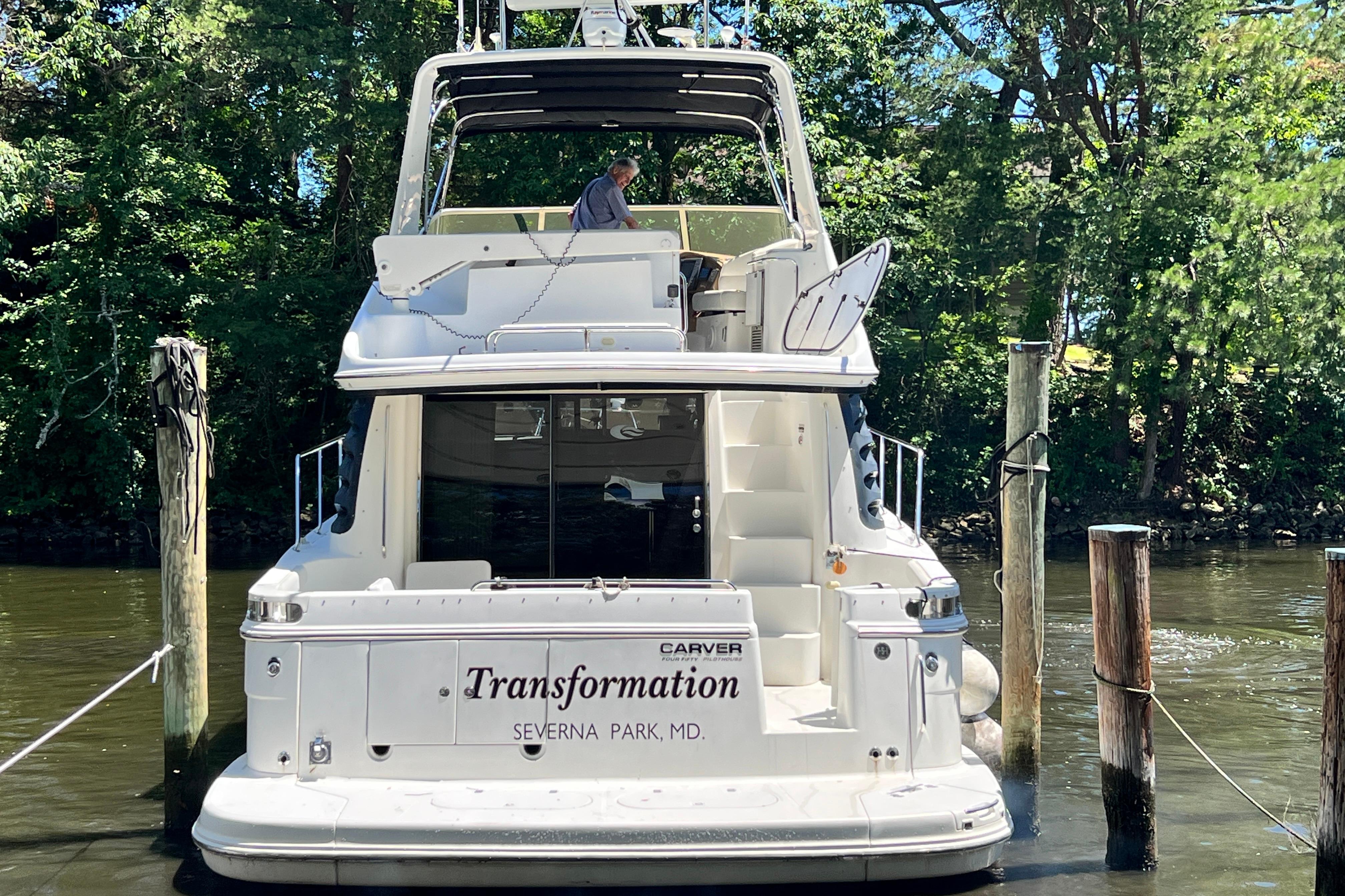 2003 Carver 450 Voyager Pilothouse yacht docked, named "Transformation," in a serene wooded area.