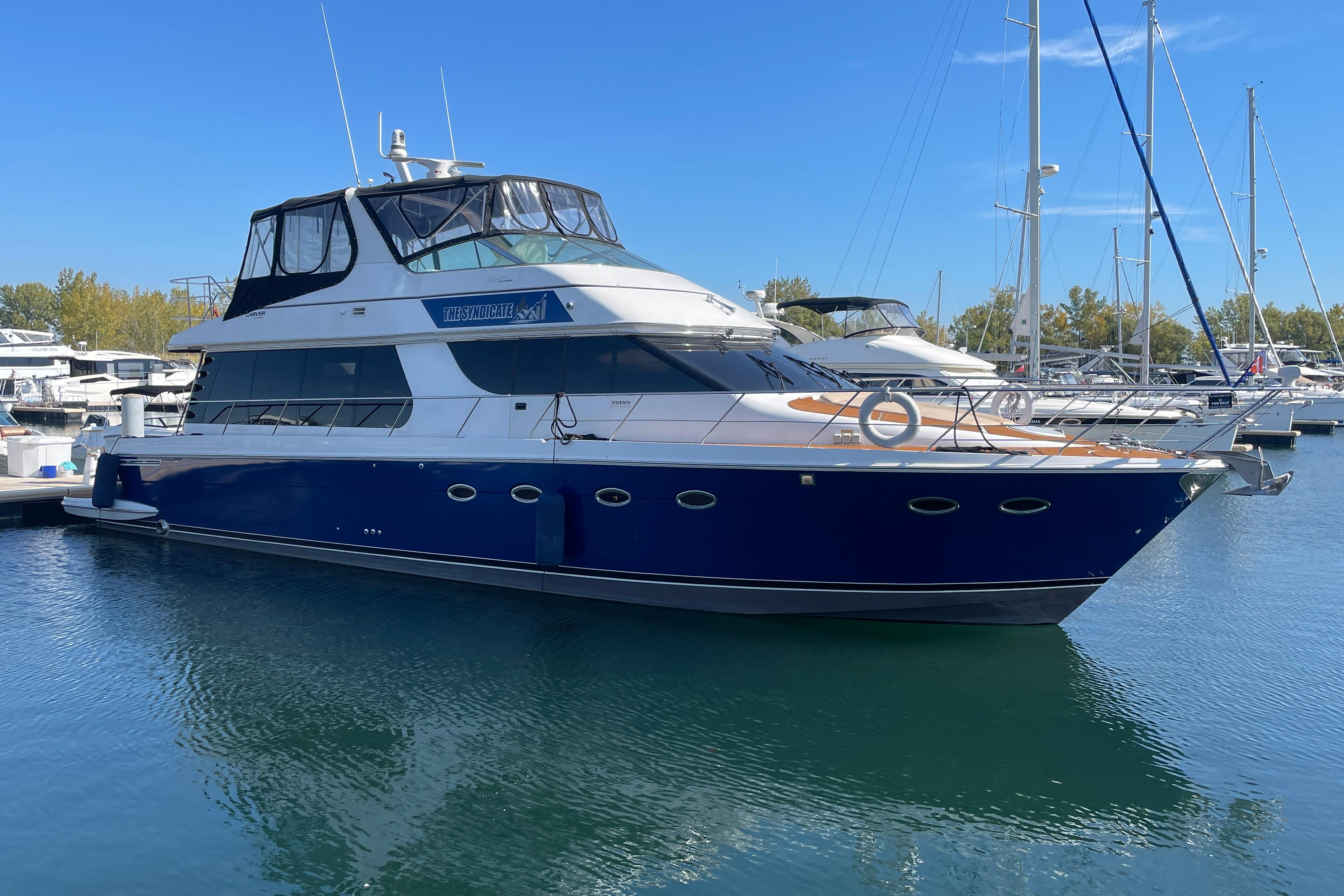 2002 Carver 570 Voyager Pilothouse yacht docked in a marina under clear blue skies.
