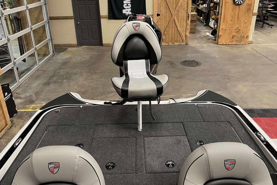 2026 Triton 18 TrX boat interior with gray and black seating in a garage setting.