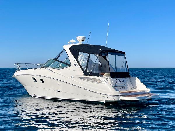 2014 Sea Ray 330 Sundancer cruising on open water under clear blue sky.