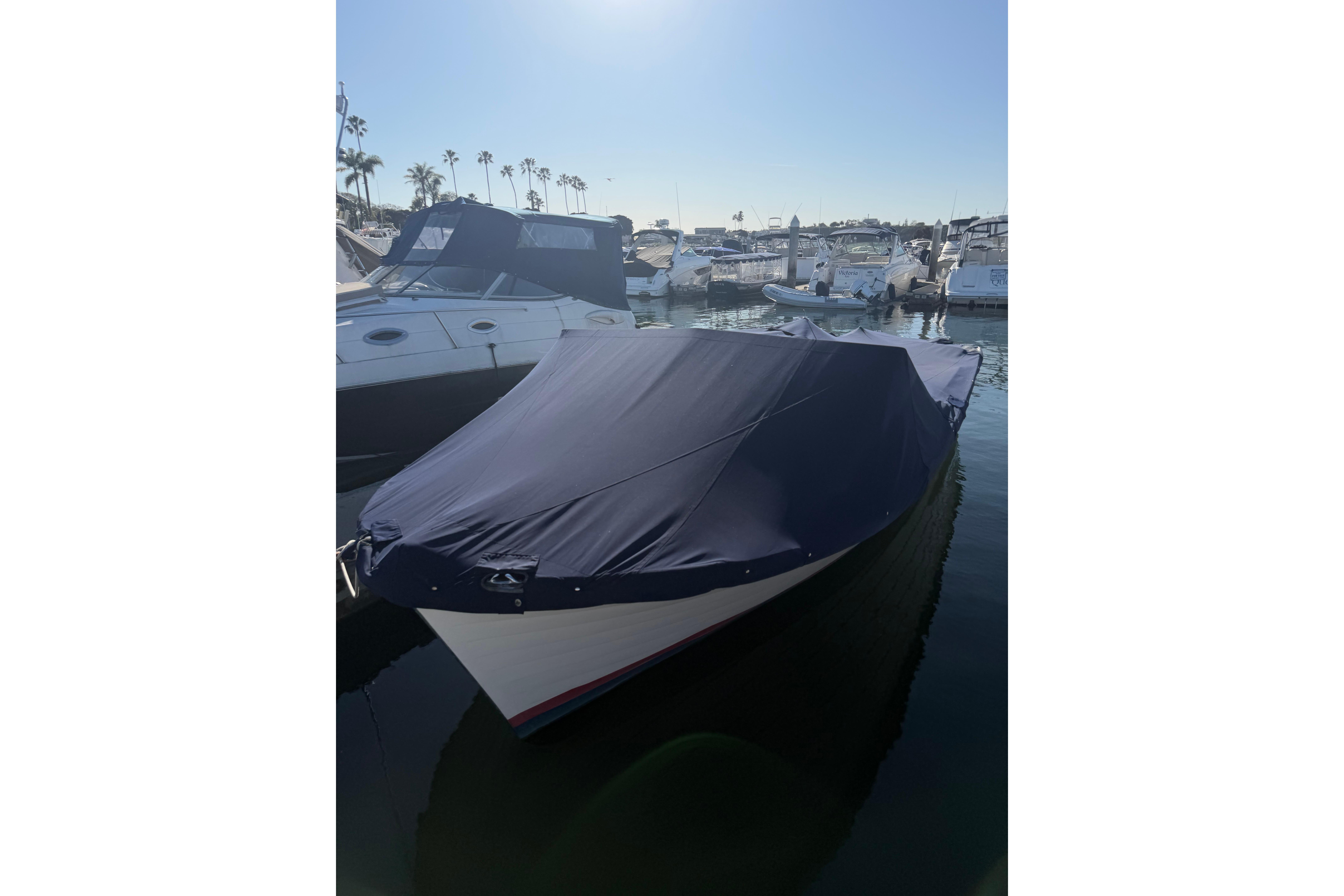 1964 Lyman 25 Sleeper boat covered at marina, surrounded by other vessels.