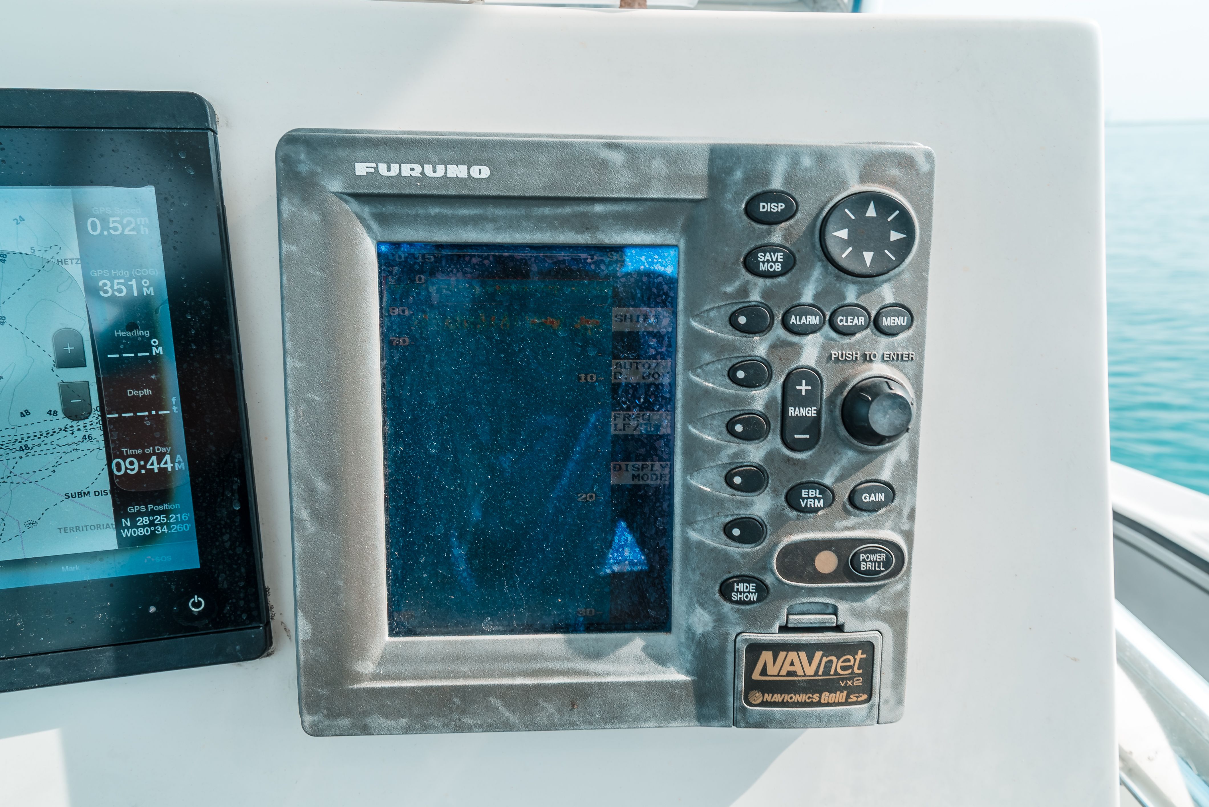 Navigation system on a boat with Furuno screen and control buttons.