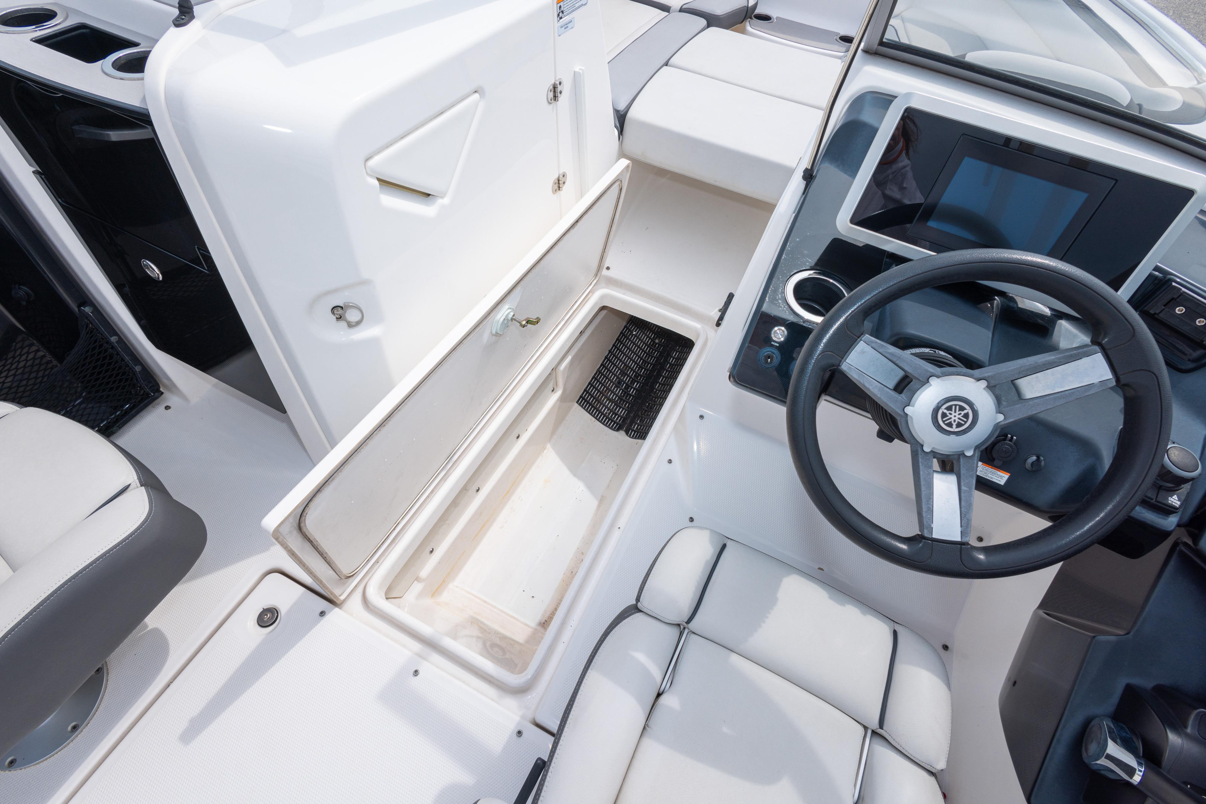 2021 Yamaha Boats AR250 interior with steering wheel, storage compartment, and seating.