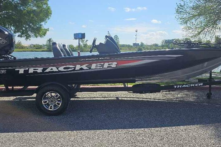2026 Tracker Pro Team 190 boat on trailer by a lake, under clear blue sky.