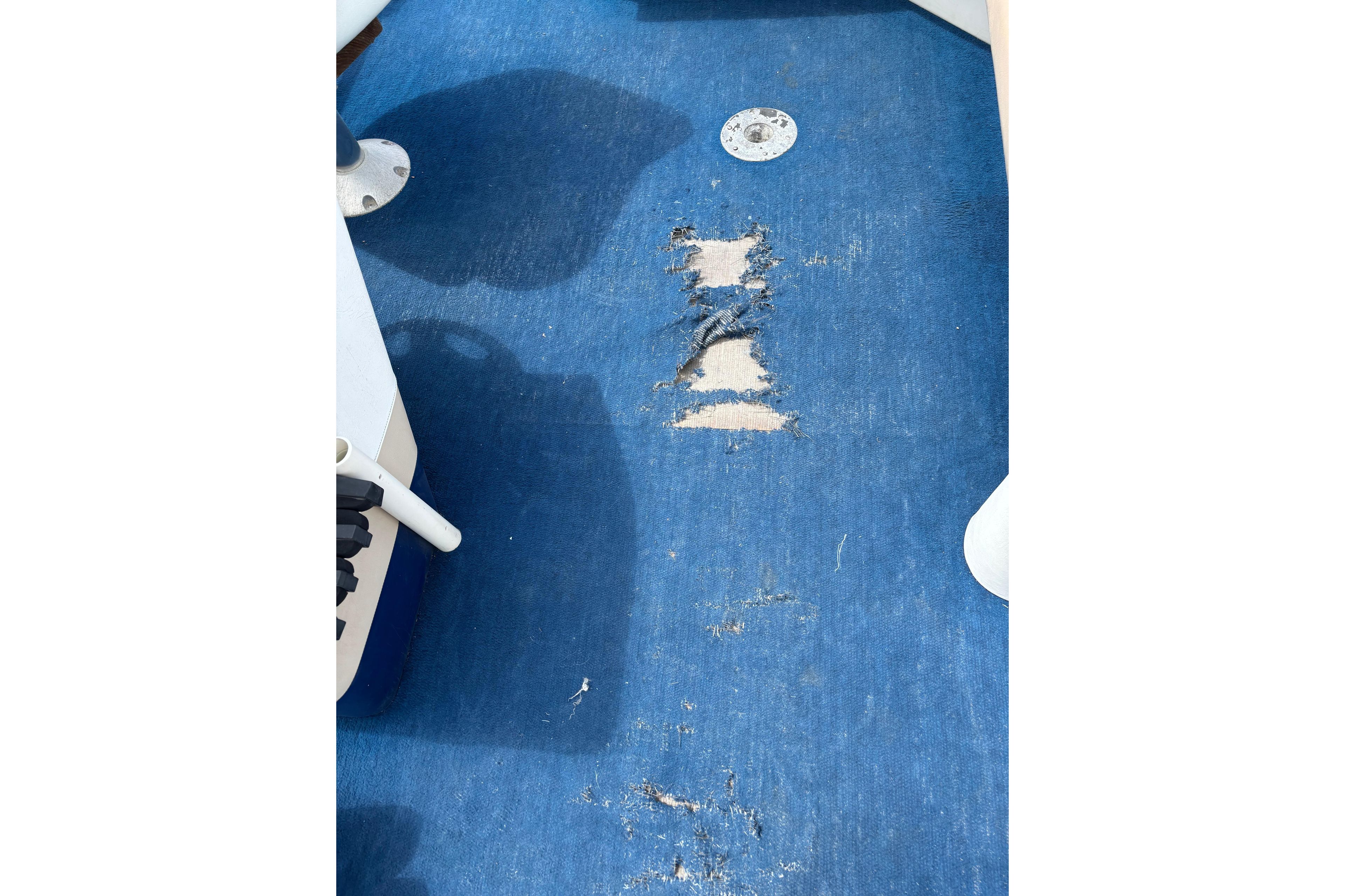 Worn blue carpet on 1997 Northwood 24' Pontoon boat floor, showing visible damage.