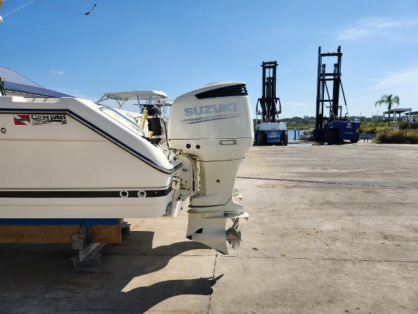 2005 Pursuit 3070 Offshore Center Console with Suzuki outboard motor on a sunny dock.