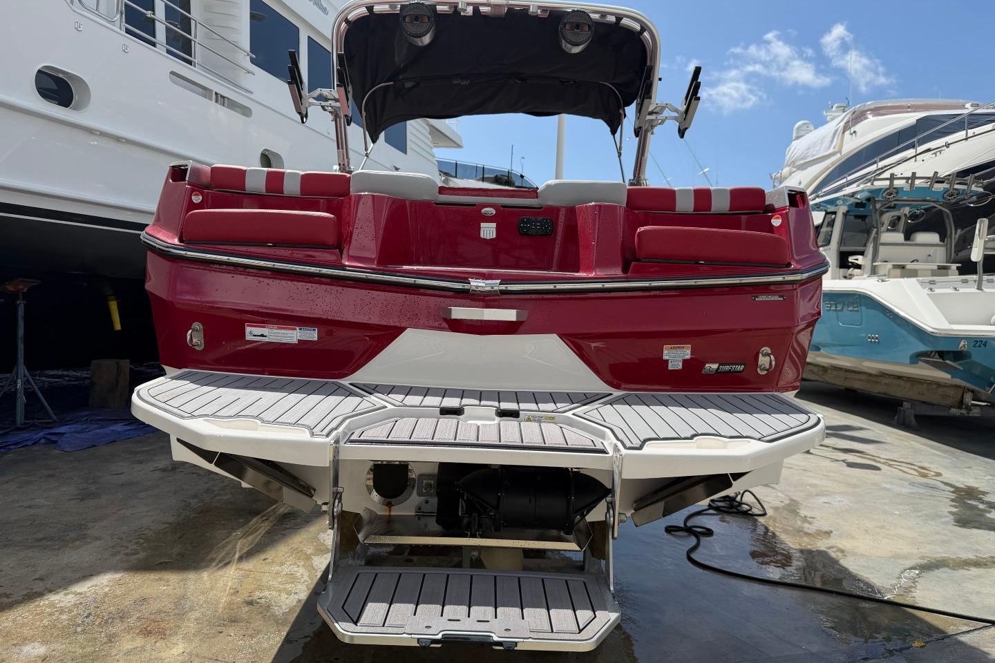 2023 MasterCraft X24 boat, red exterior, docked with swim platform, sunny day.
