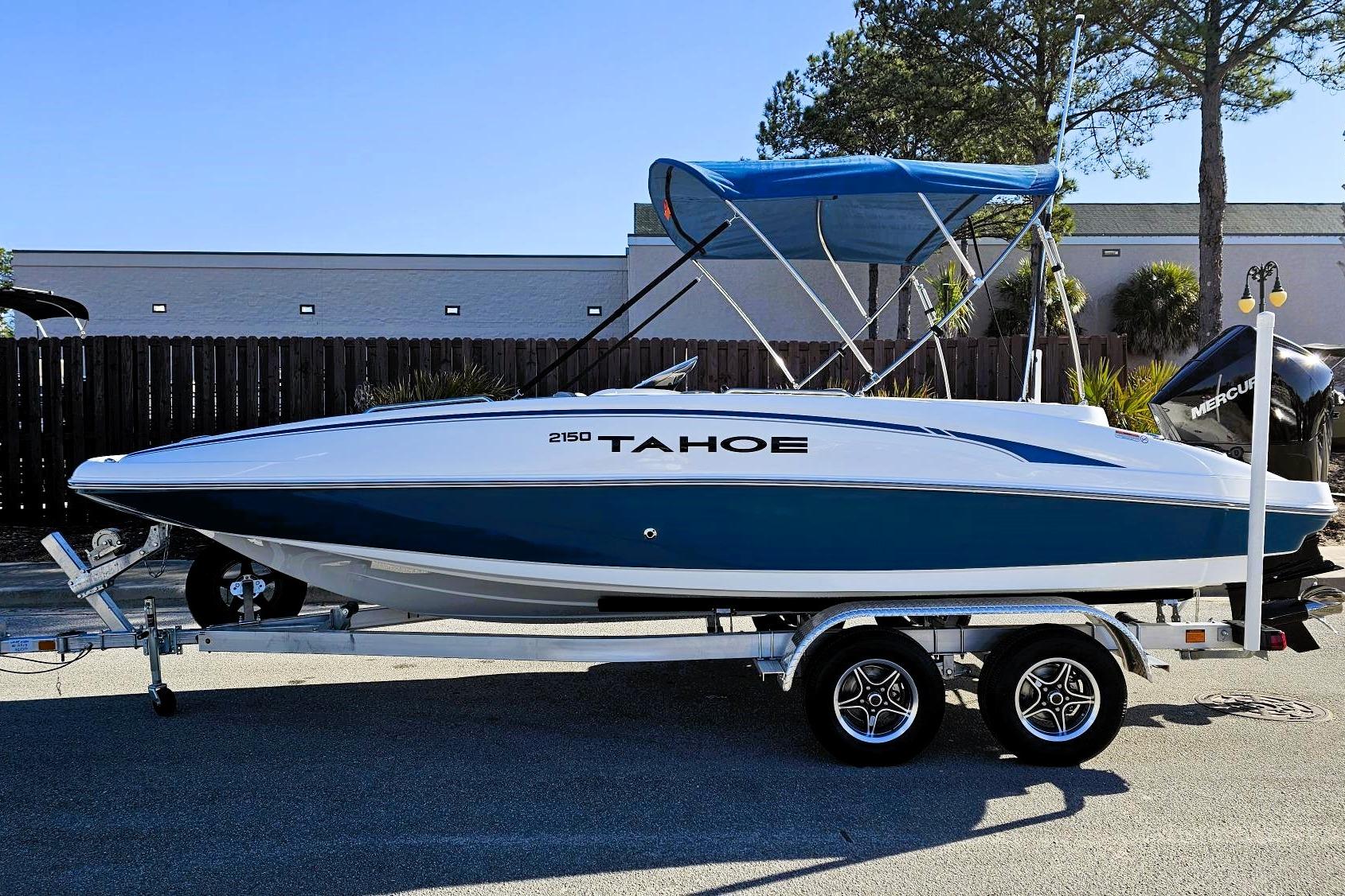 2026 Tahoe 2150 boat on trailer with blue canopy, parked outdoors.