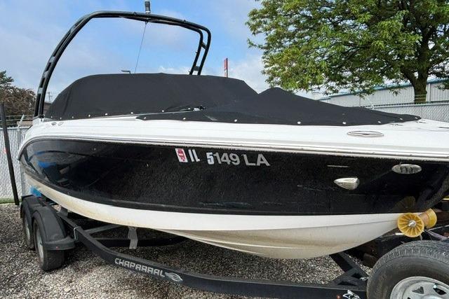 2021 Chaparral 21 SSi boat on trailer, black cover, parked outdoors.