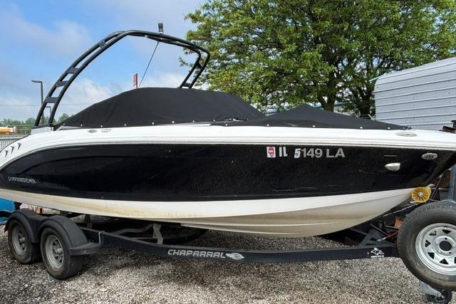 2021 Chaparral 21 SSi boat on trailer, black cover, parked outdoors.