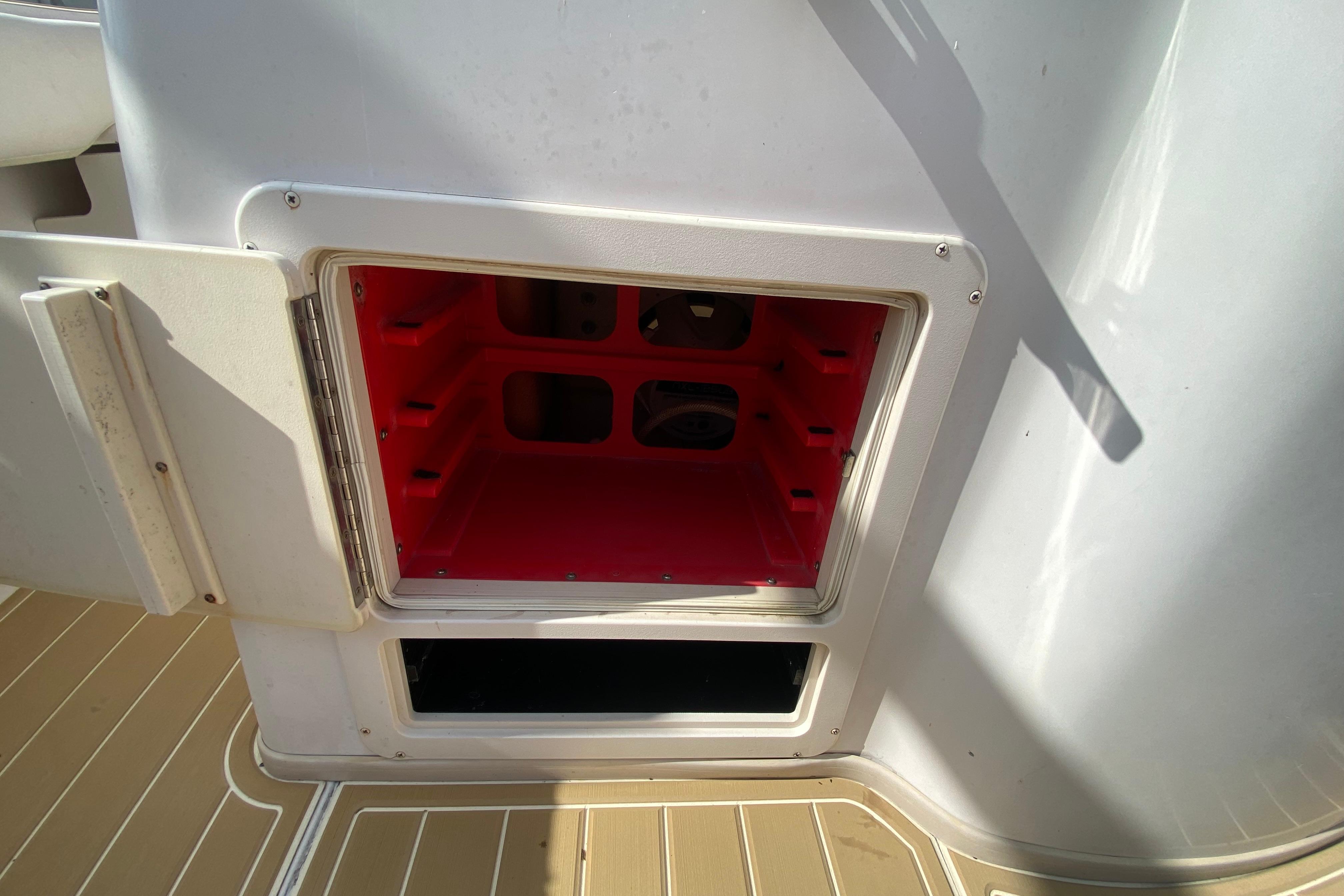 Open storage compartment on 2004 Grady-White Canyon 283 boat, featuring red interior.