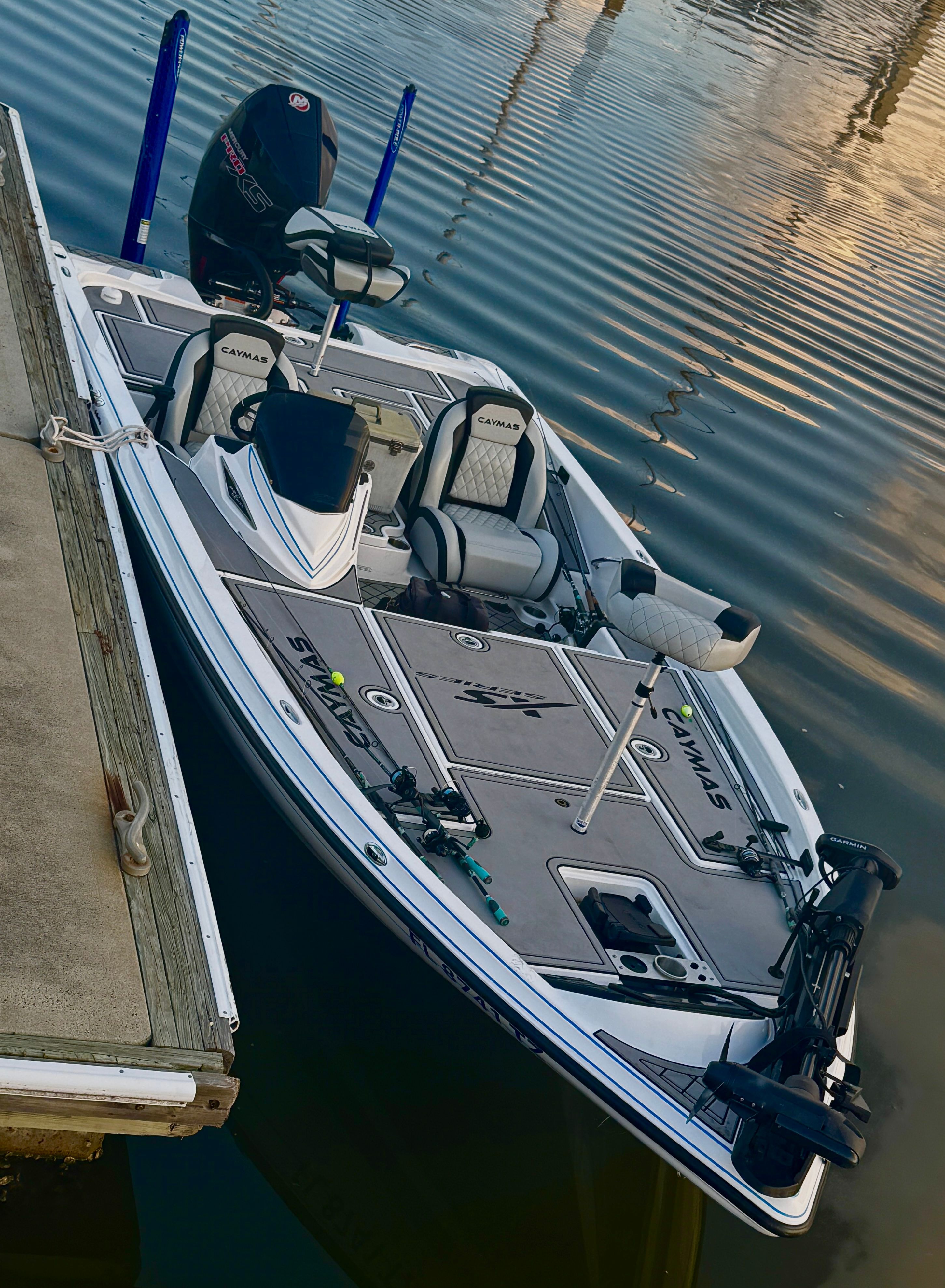 A 2025 Caymas CS-20 boat docked. It features a sleek design and is equipped with fishing rods.