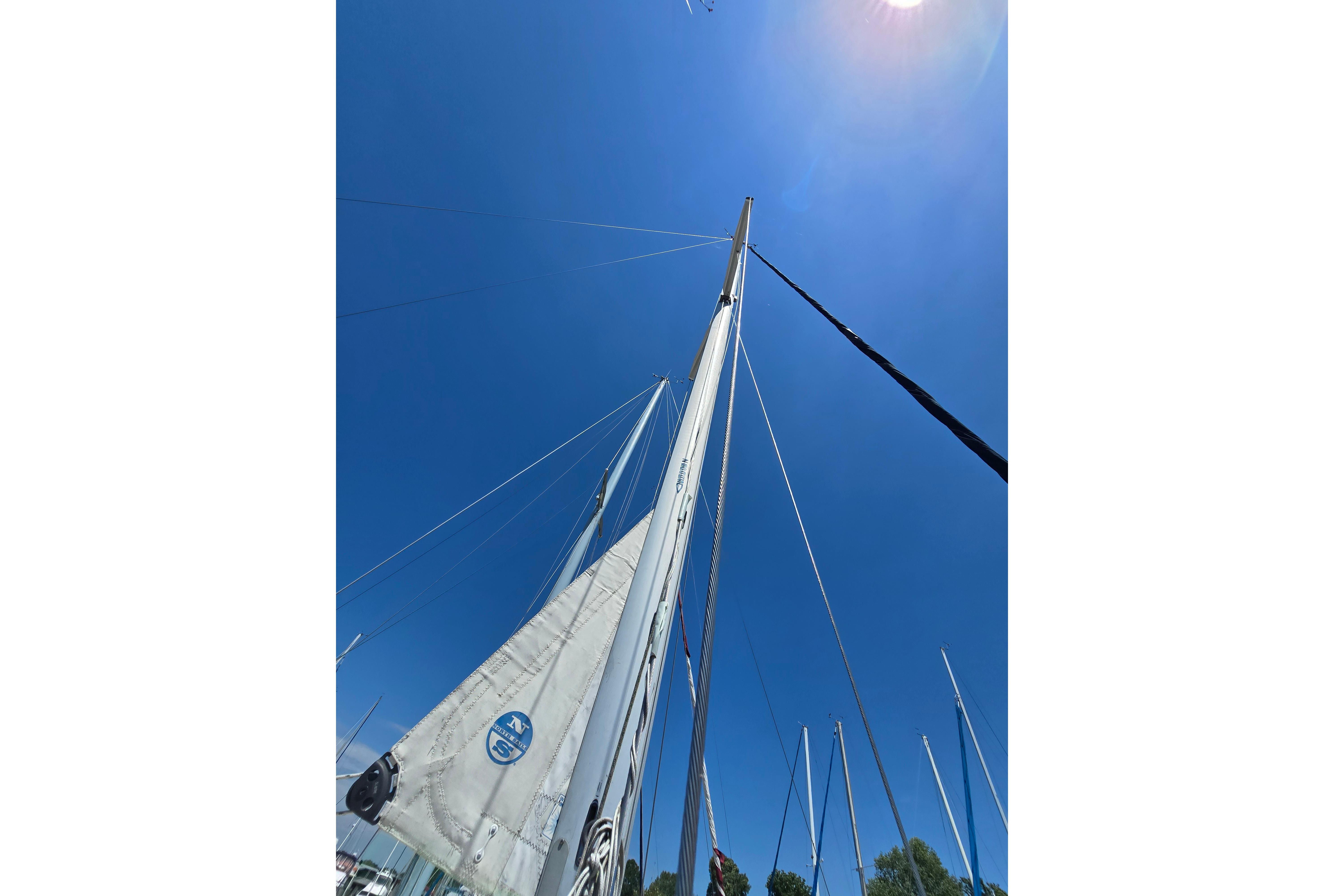 Sailboat mast and sails of a 1993 Caliber 35 against a clear blue sky.