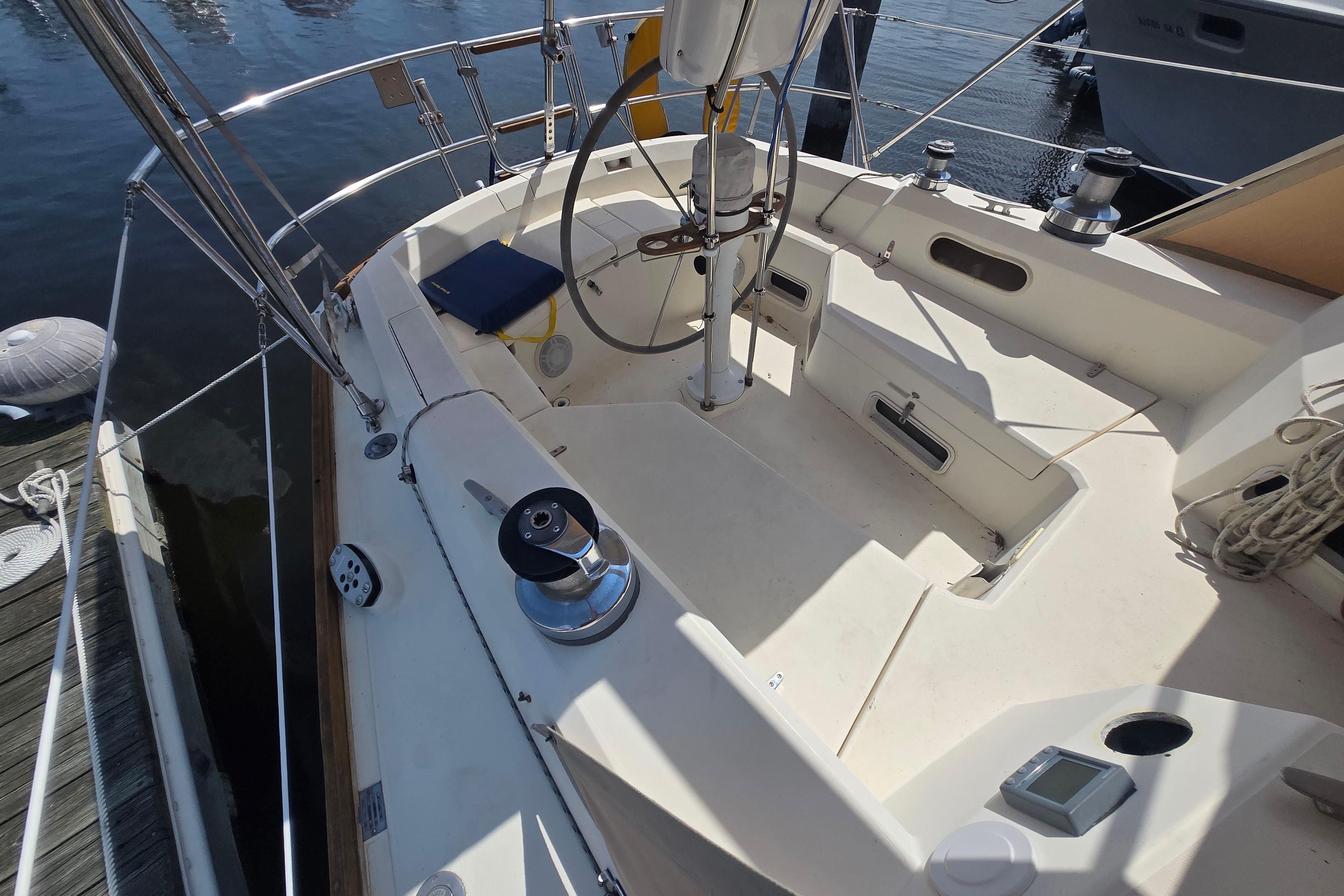 1988 Sabre 38 sailboat cockpit with steering wheel and winches, docked at marina.