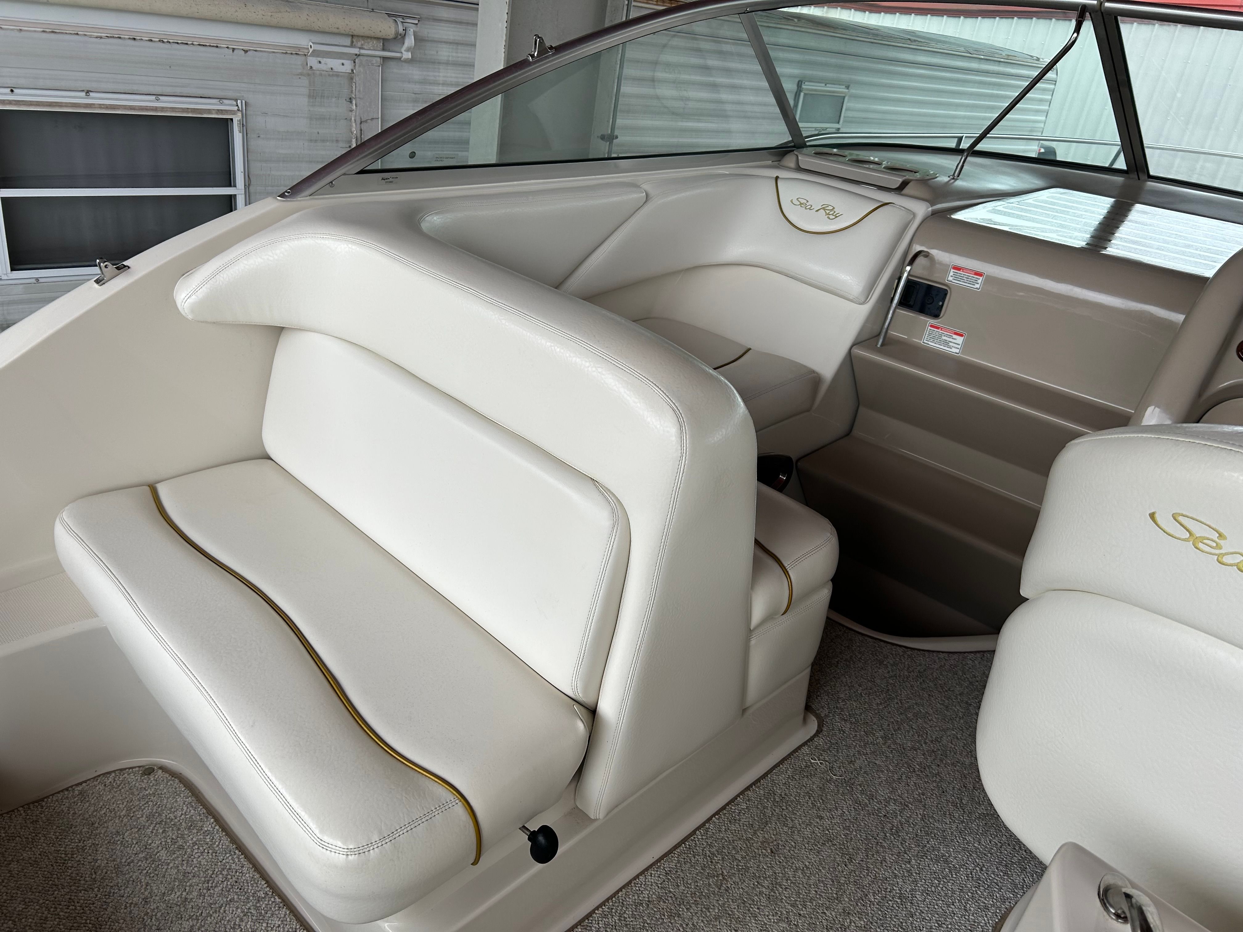 2003 Sea Ray 240 Sundancer interior with white seating and dashboard details.