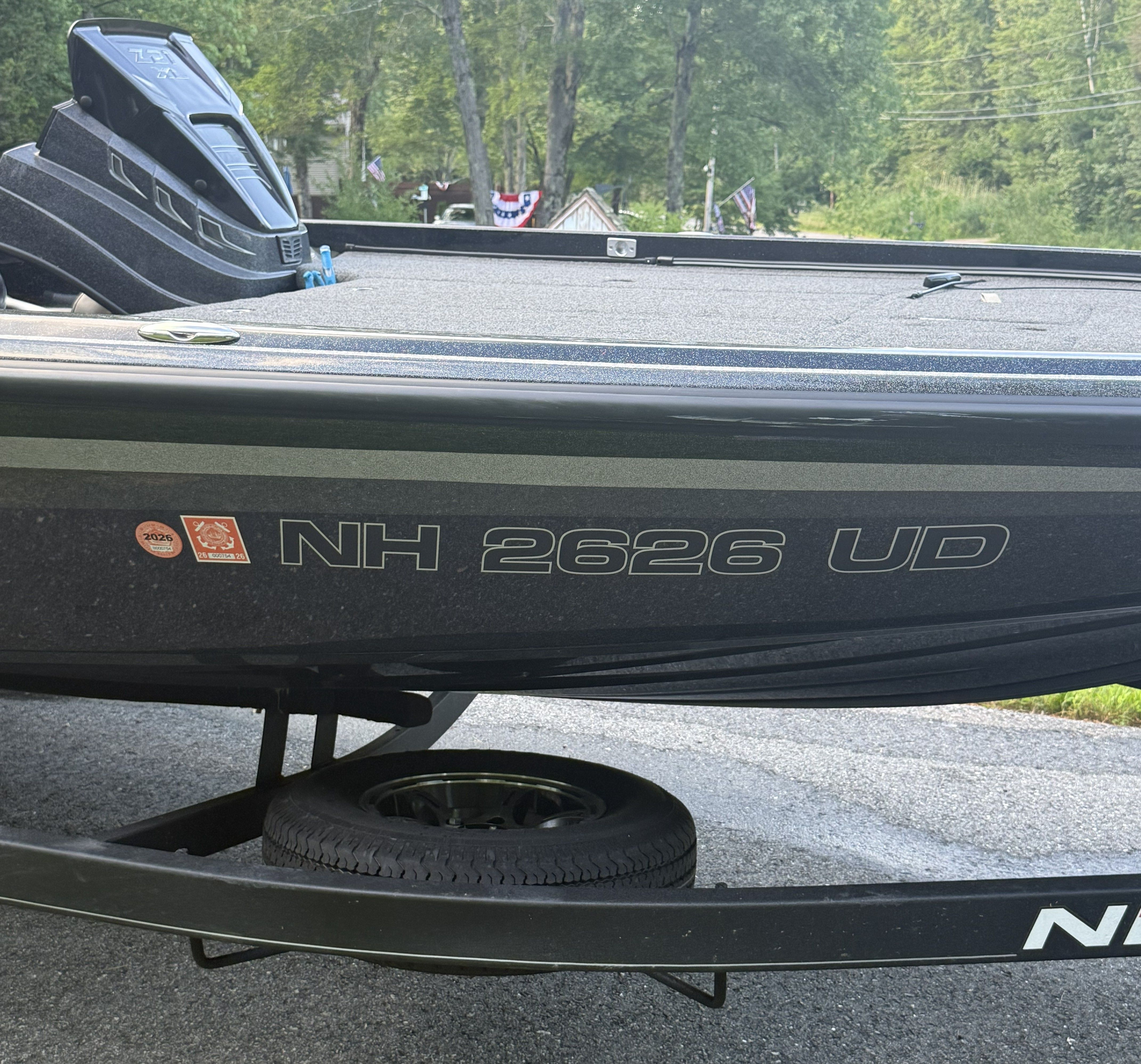 A 2023 Nitro Z21 XL Pro boat on a trailer, surrounded by trees and houses.