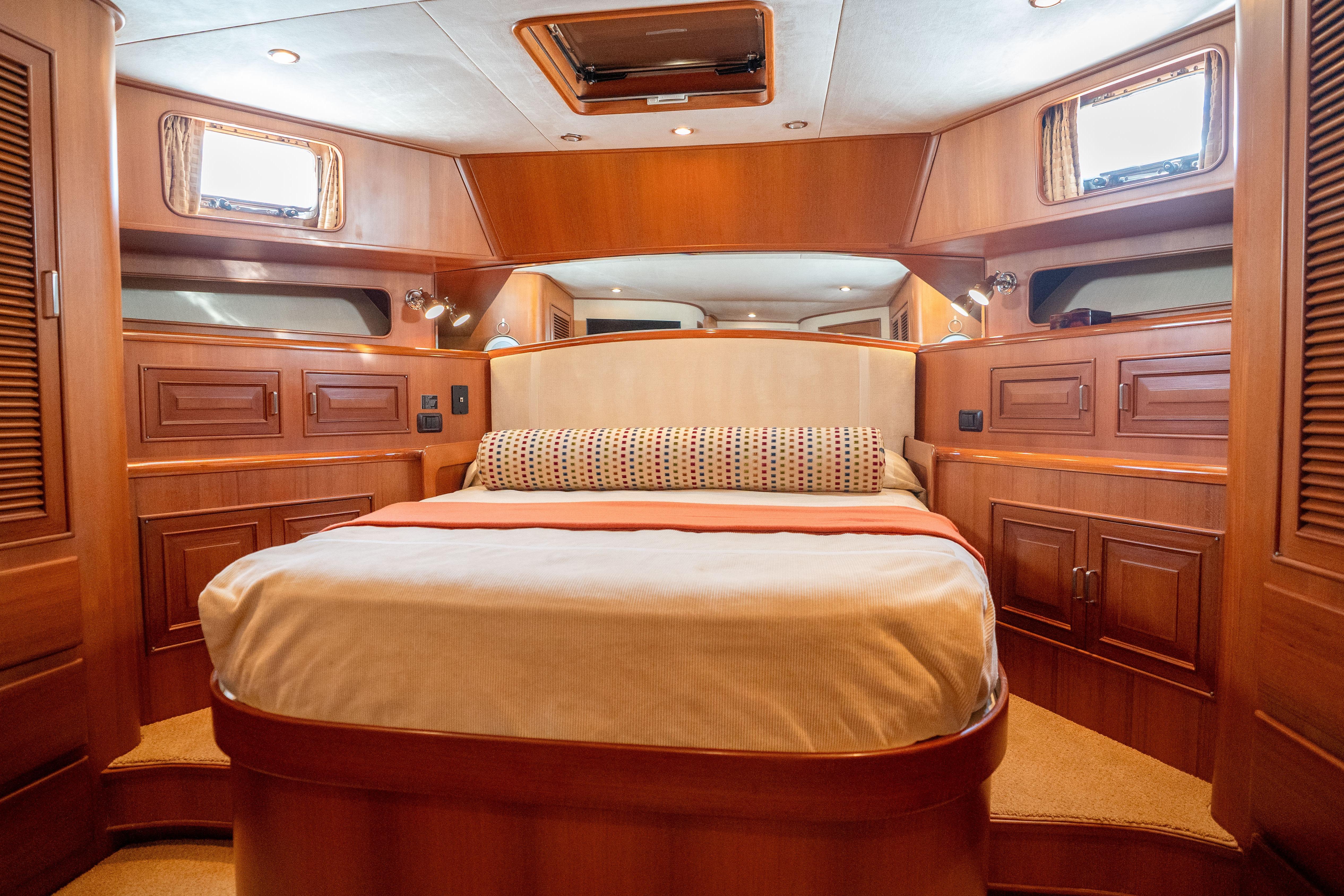 Luxurious 2006 Fleming 75 yacht bedroom with elegant wood paneling and cozy bedding.