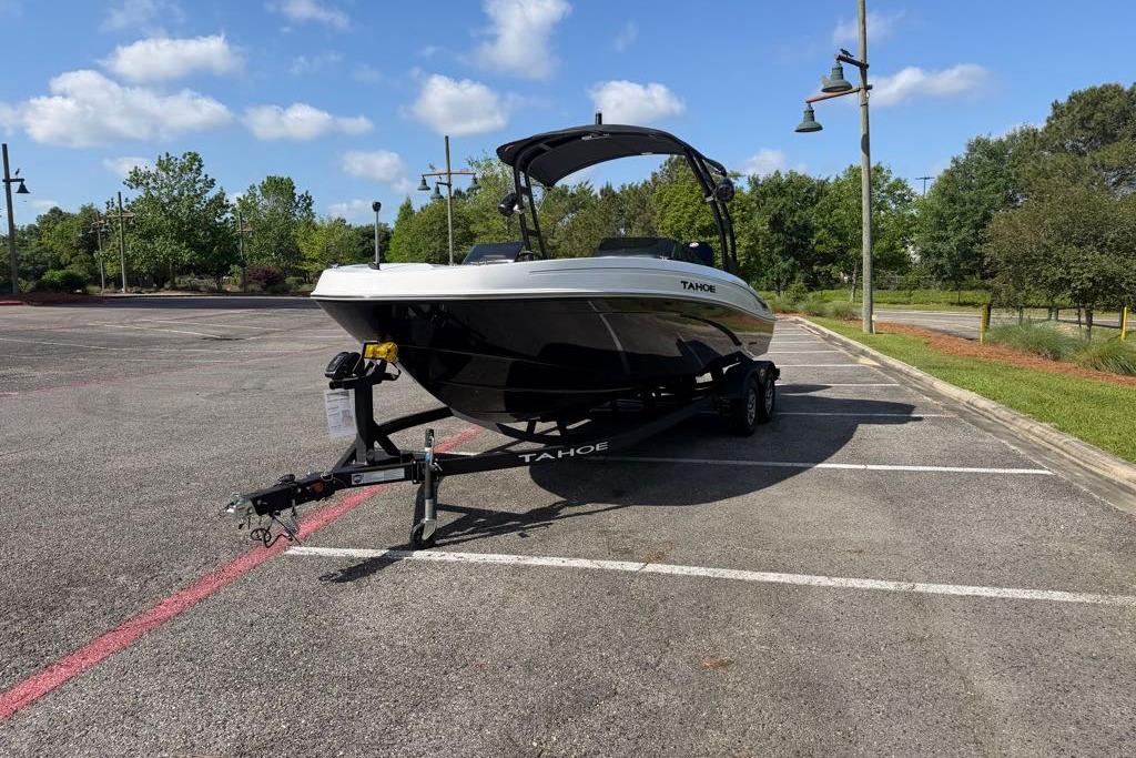 2026 Tahoe T21 boat on trailer in parking lot, surrounded by trees and blue sky.