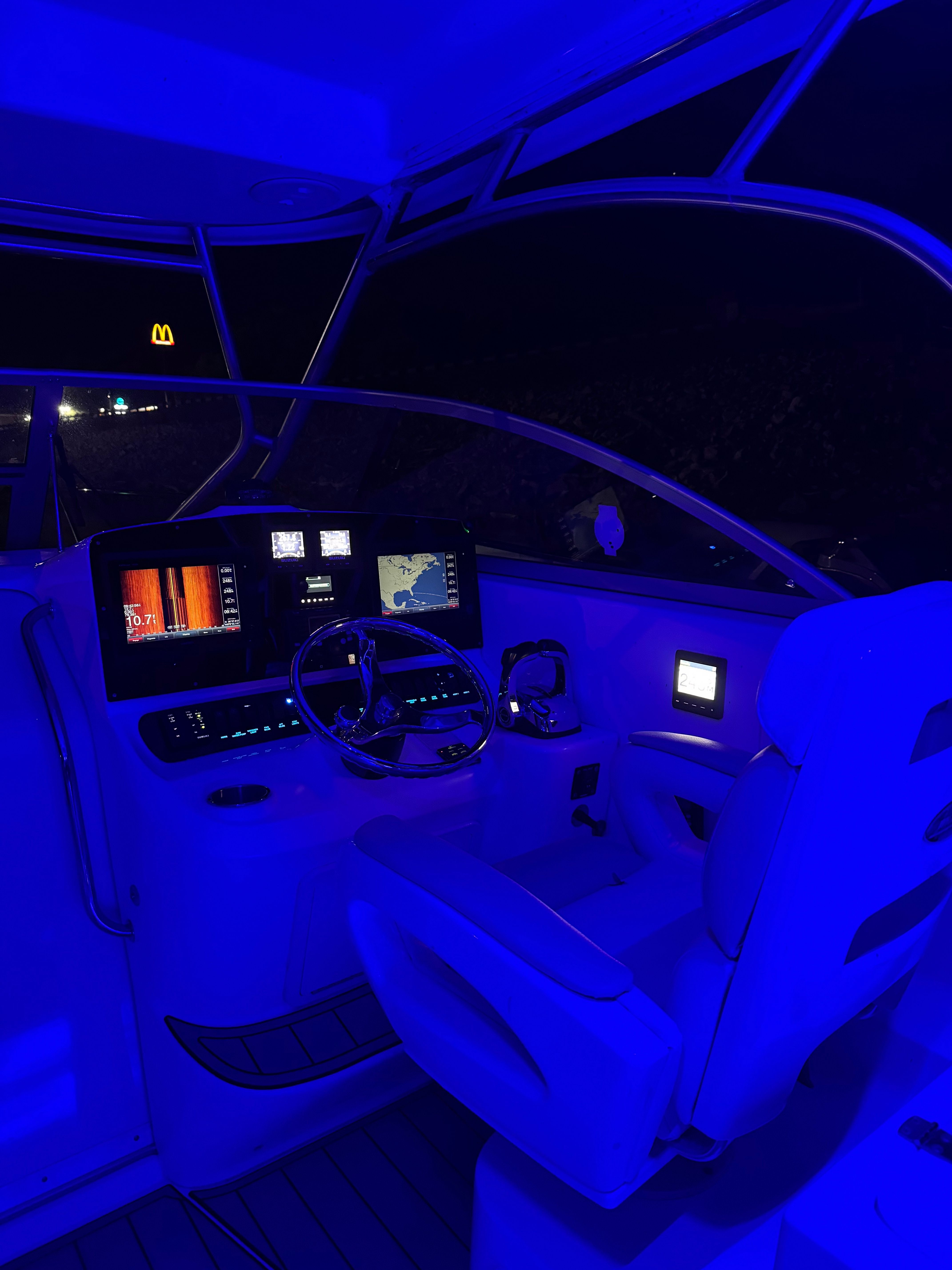 The cockpit of a 2006 Boston Whaler 305 Conquest at night with blue lighting.