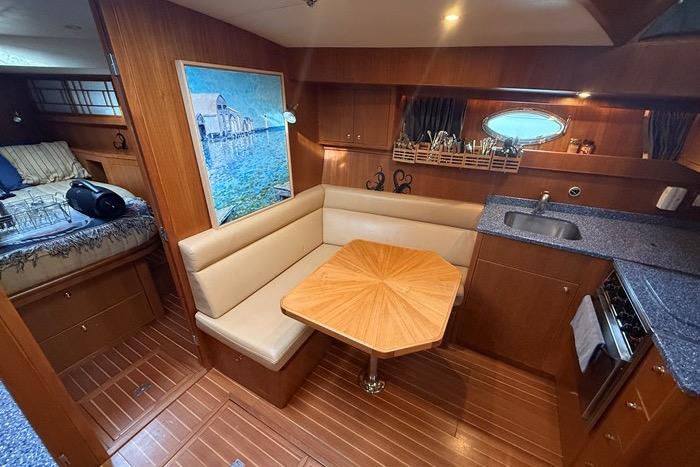 2007 Island Pilot 395 interior with dining area, kitchenette, and cozy sleeping quarters.