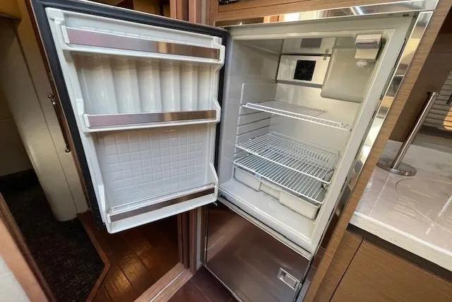 Open refrigerator inside 2016 Sea Ray Sundancer 510 yacht, showcasing spacious interior shelves.
