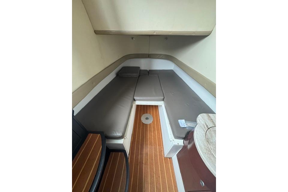 Interior cabin of 2016 Mystic M4200 boat with cushioned seating and wooden flooring.
