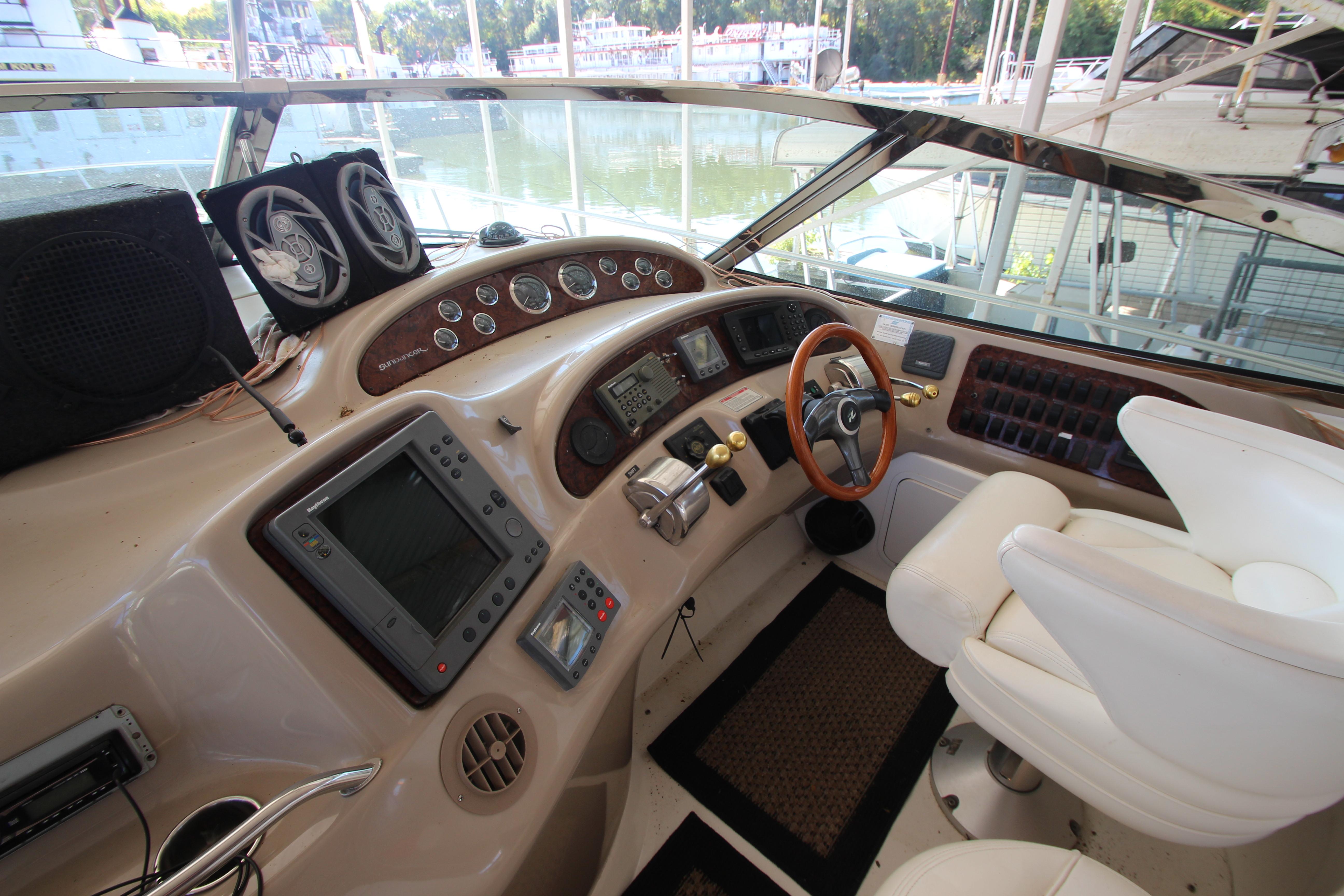 2001 Sea Ray 460 Sundancer helm with modern navigation equipment and white captain's chairs.