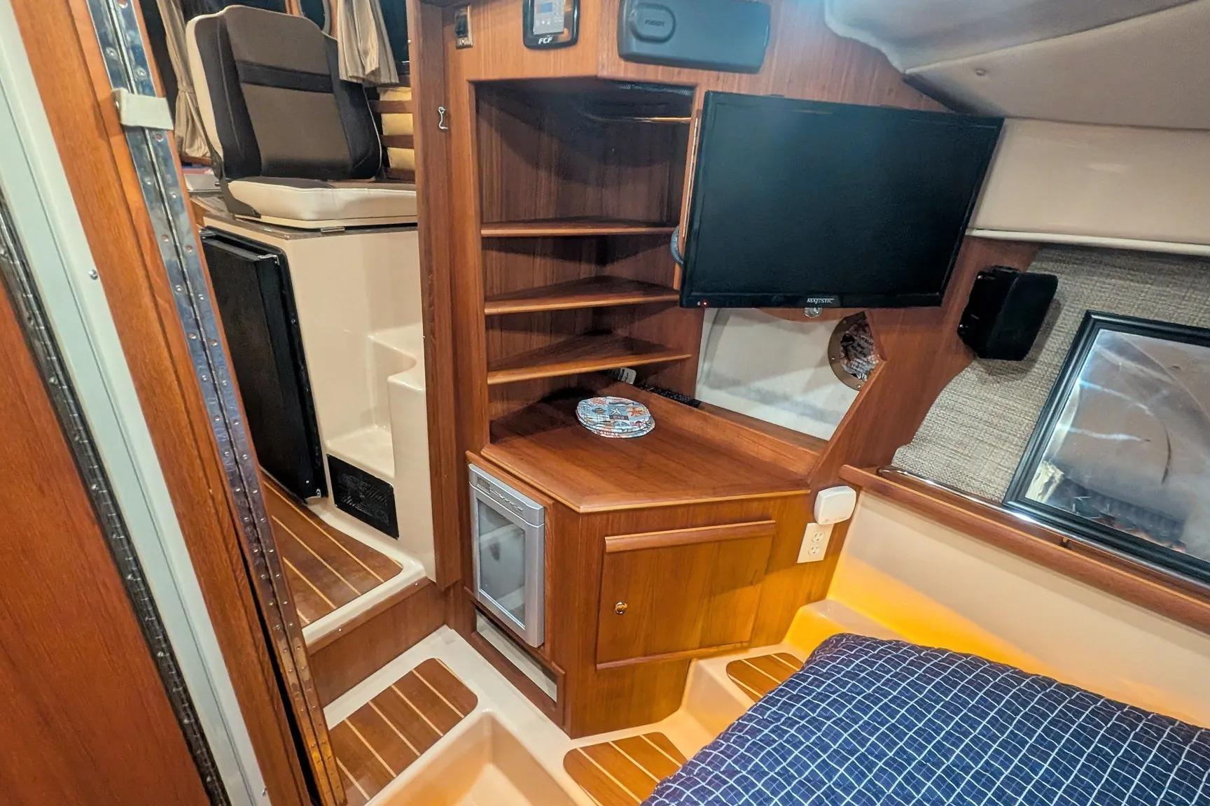 2015 Ranger Tugs R-29 S interior with wood cabinetry, TV, and seating area.