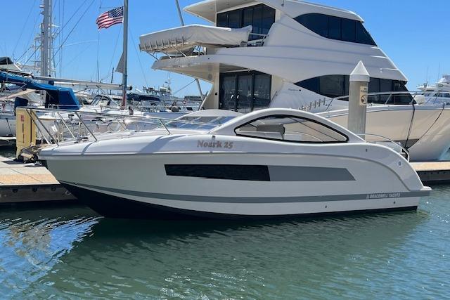 2024 Bracewell 25 boat docked at marina, sleek design, sunny day, American flag in background.