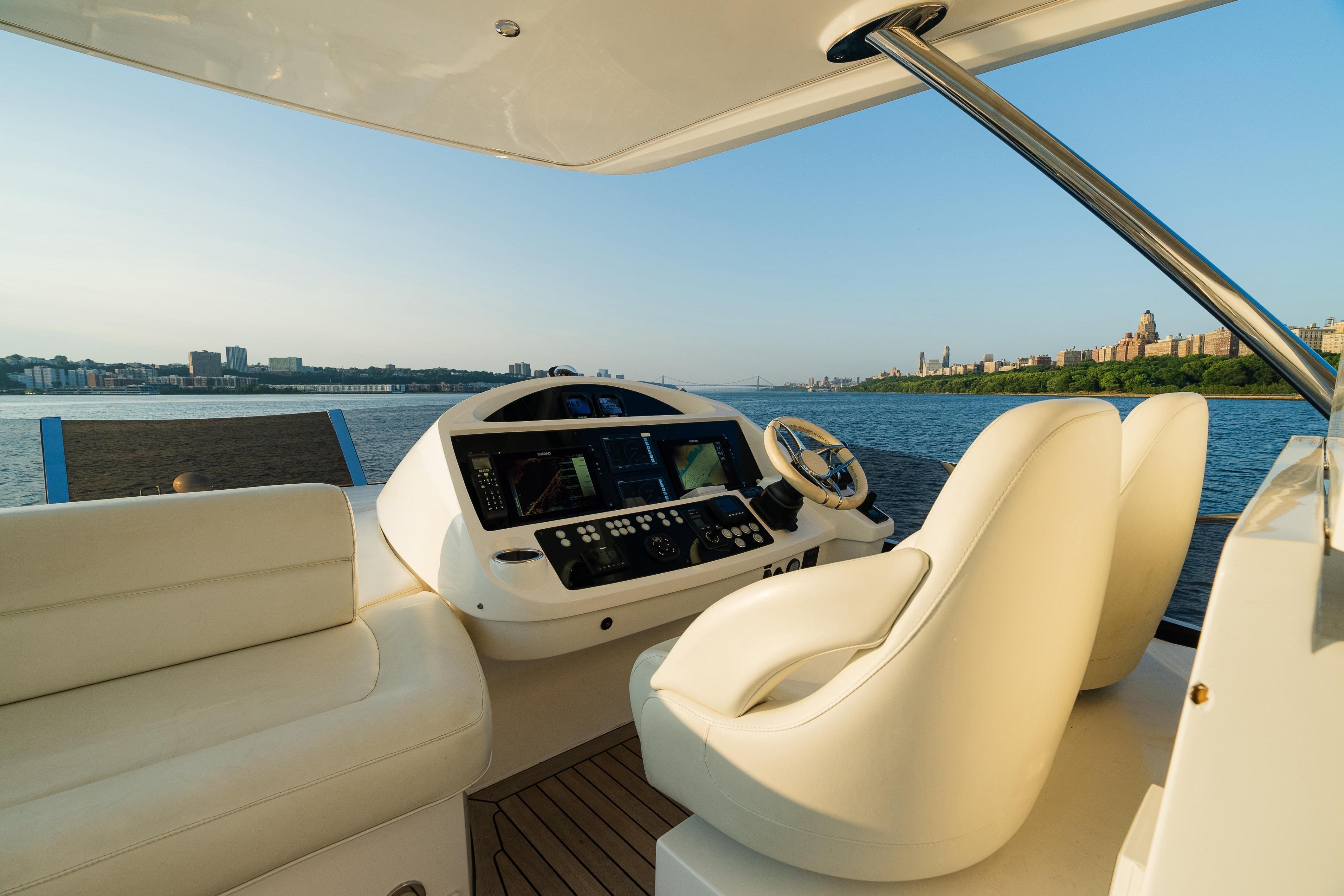 Luxurious 2016 Sunseeker Manhattan 65 yacht helm with scenic waterfront view.