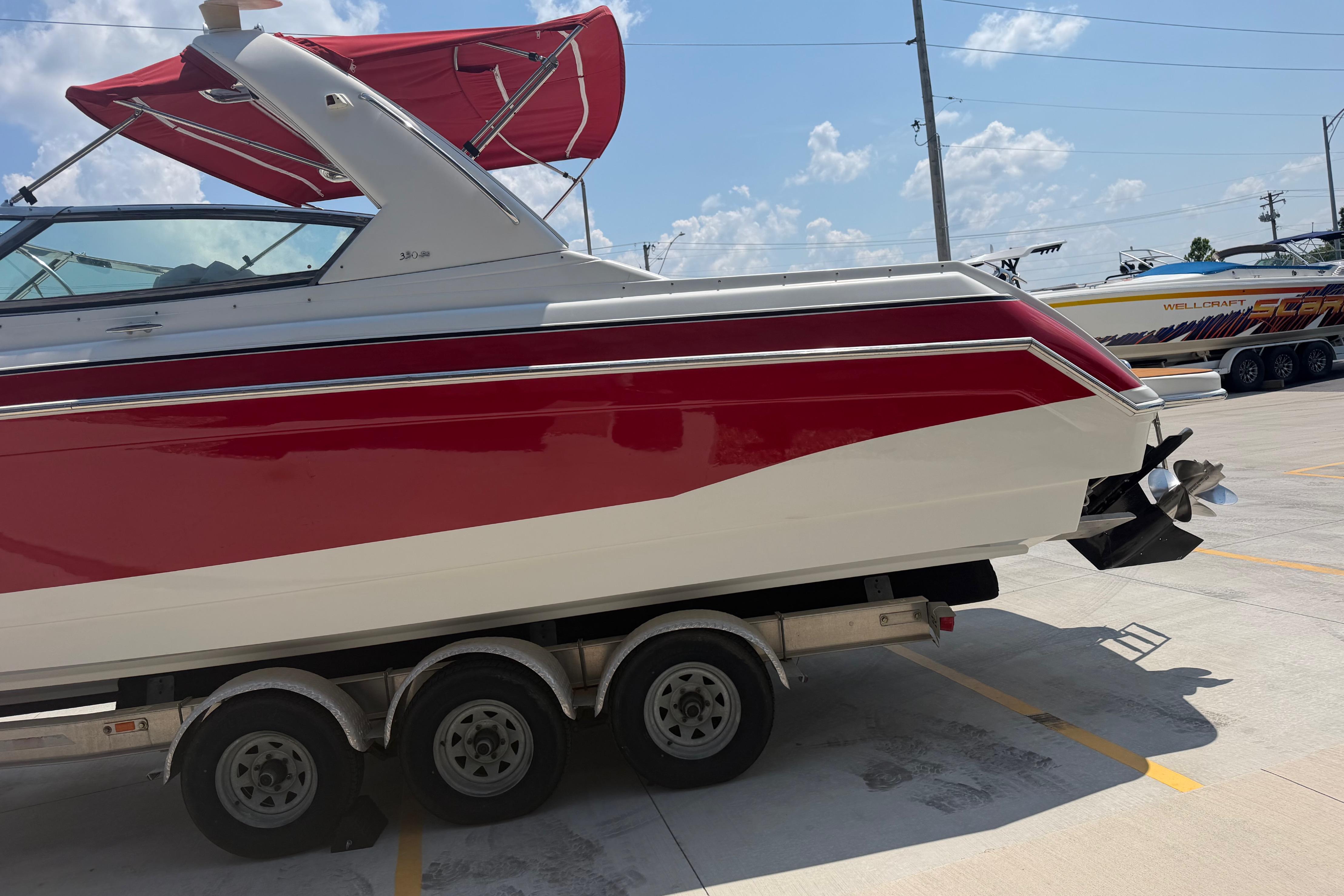 2006 Formula 330 Sun Sport boat on trailer, red and white design, parked outdoors.