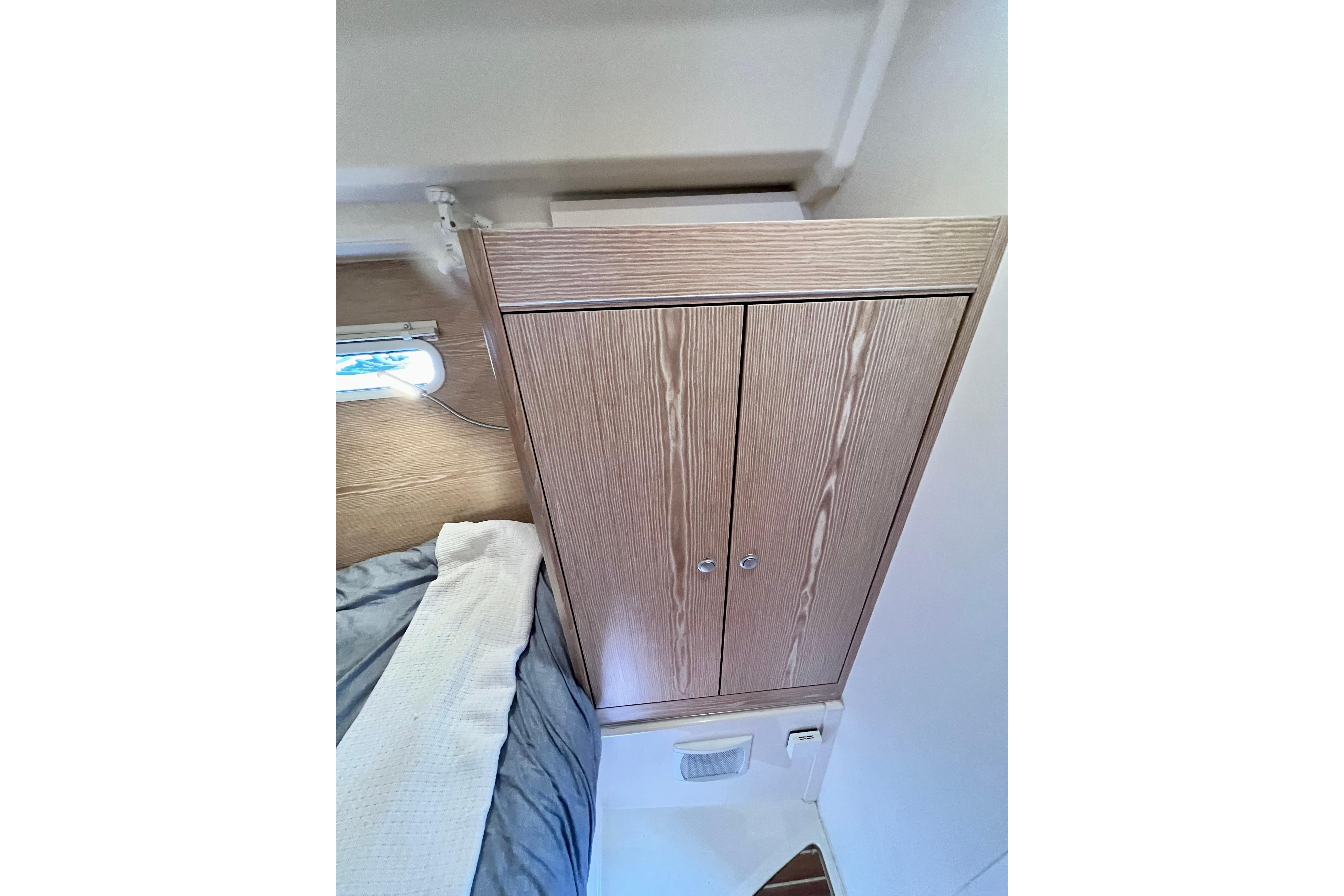 Interior of 2016 Hanse 455 yacht showing wooden cabinet and cozy bedding.