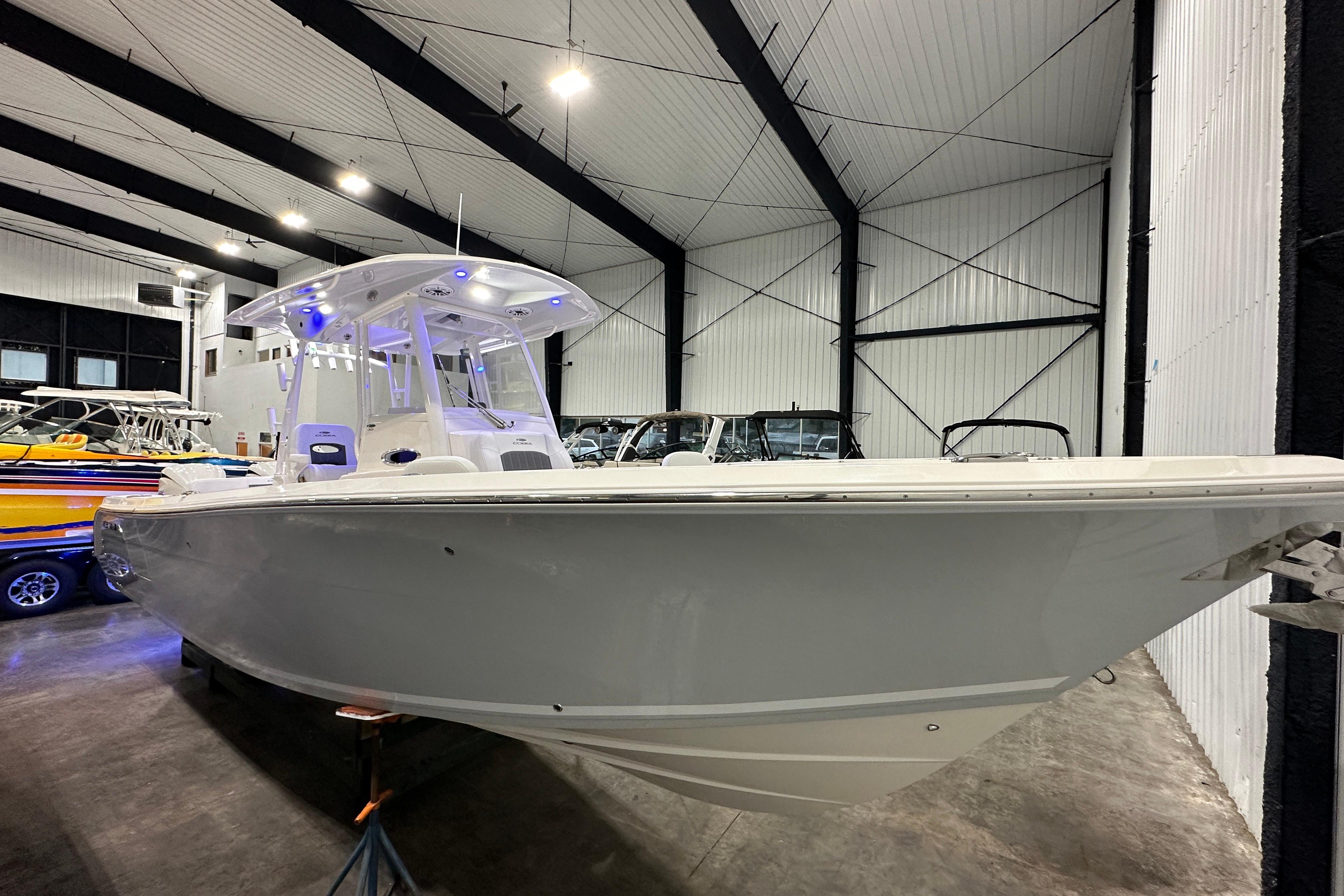 2024 Cobia 301 Center Console boat in a showroom, featuring sleek design and modern lighting.