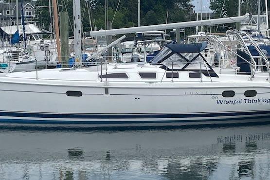 2004 Hunter 386 sailboat docked in marina, featuring sleek white design and blue accents.