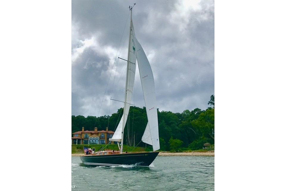 Sailing yacht Morris 36 (2006) on water near shoreline with cloudy sky.
