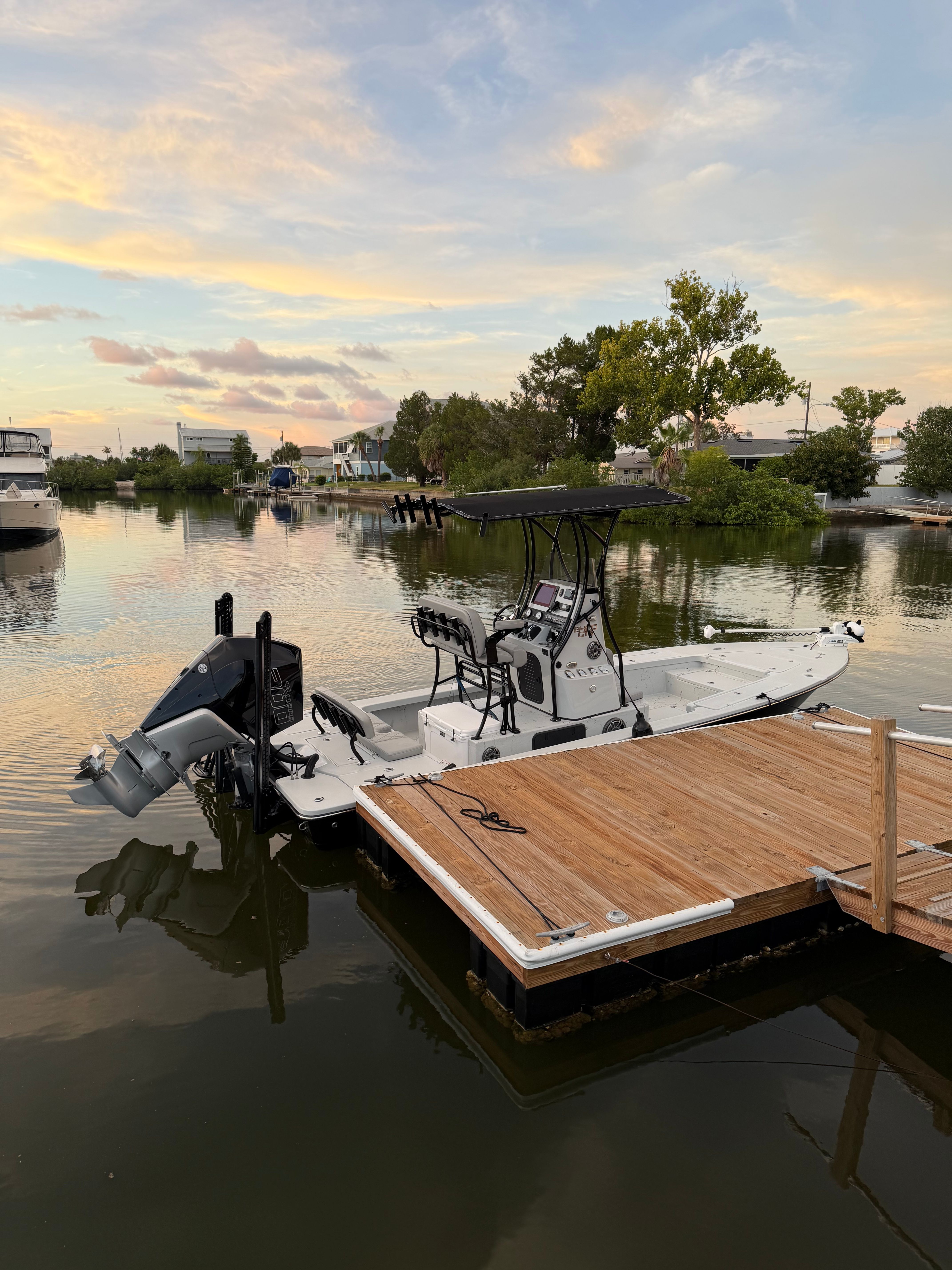 A 2022 Blazer Bay 2420 GTS docked at a wooden pier in calm water at sunset.