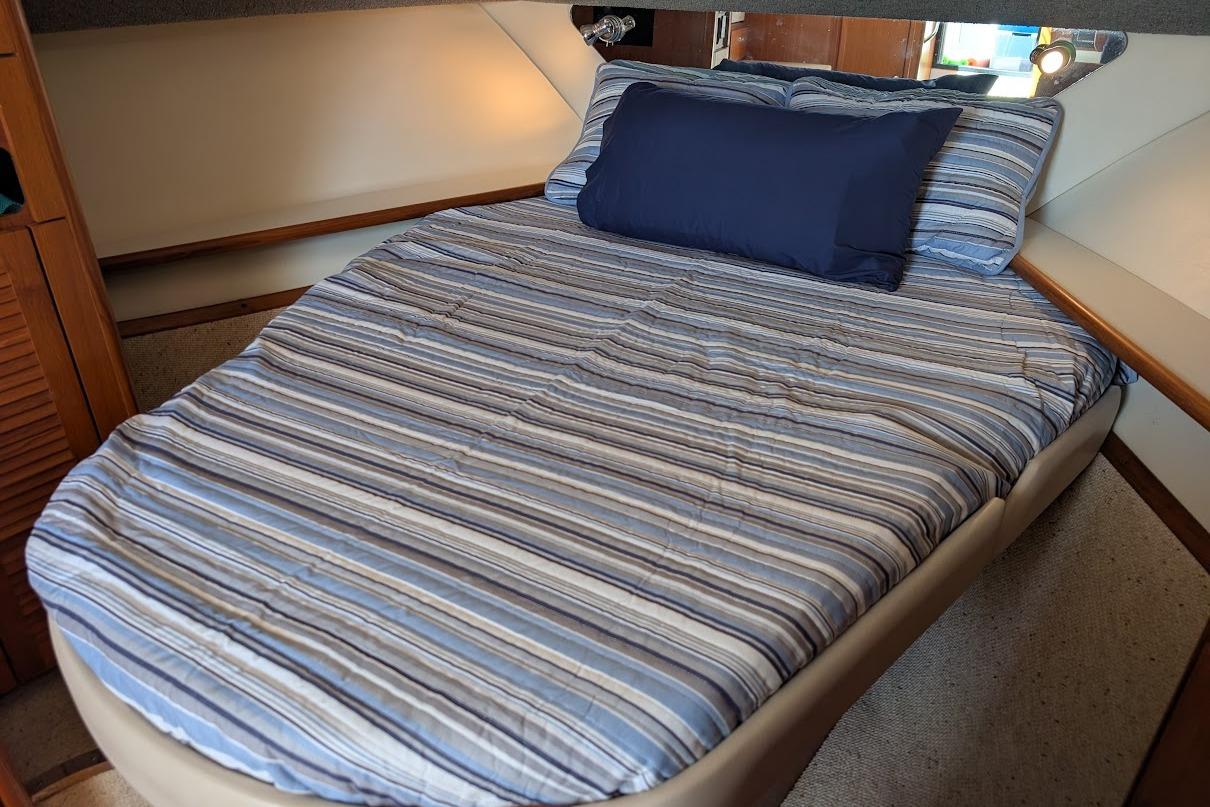 Cozy cabin bed in 2000 Pursuit 3400 Express boat with striped bedding.